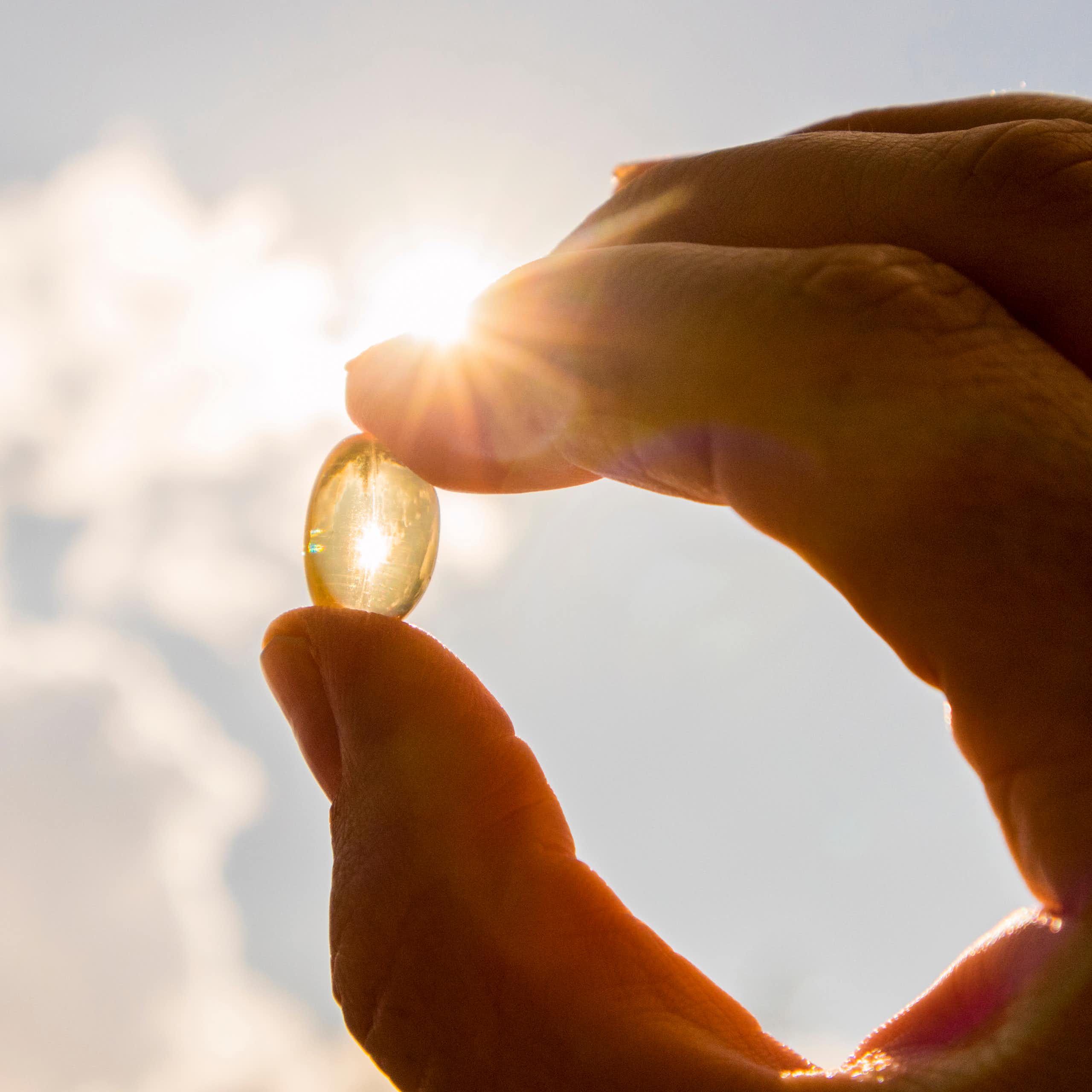 Une personne tient un complément alimentaire à base de vitamine D dont l'intérêt n'est pas établi pour les personnes en bonne santé.