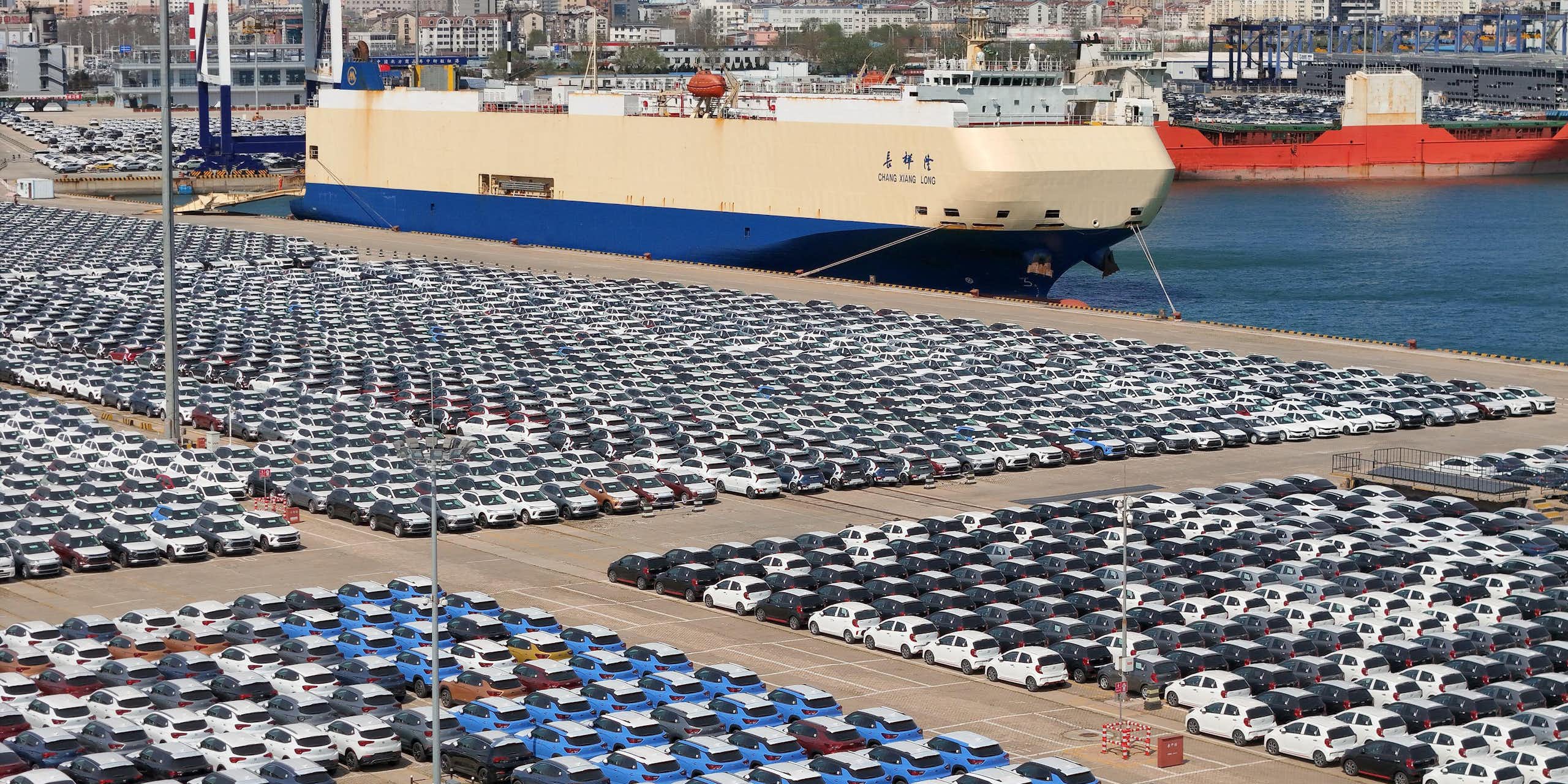 A port car park full of cars waiting to be loaded onto cargo ships.