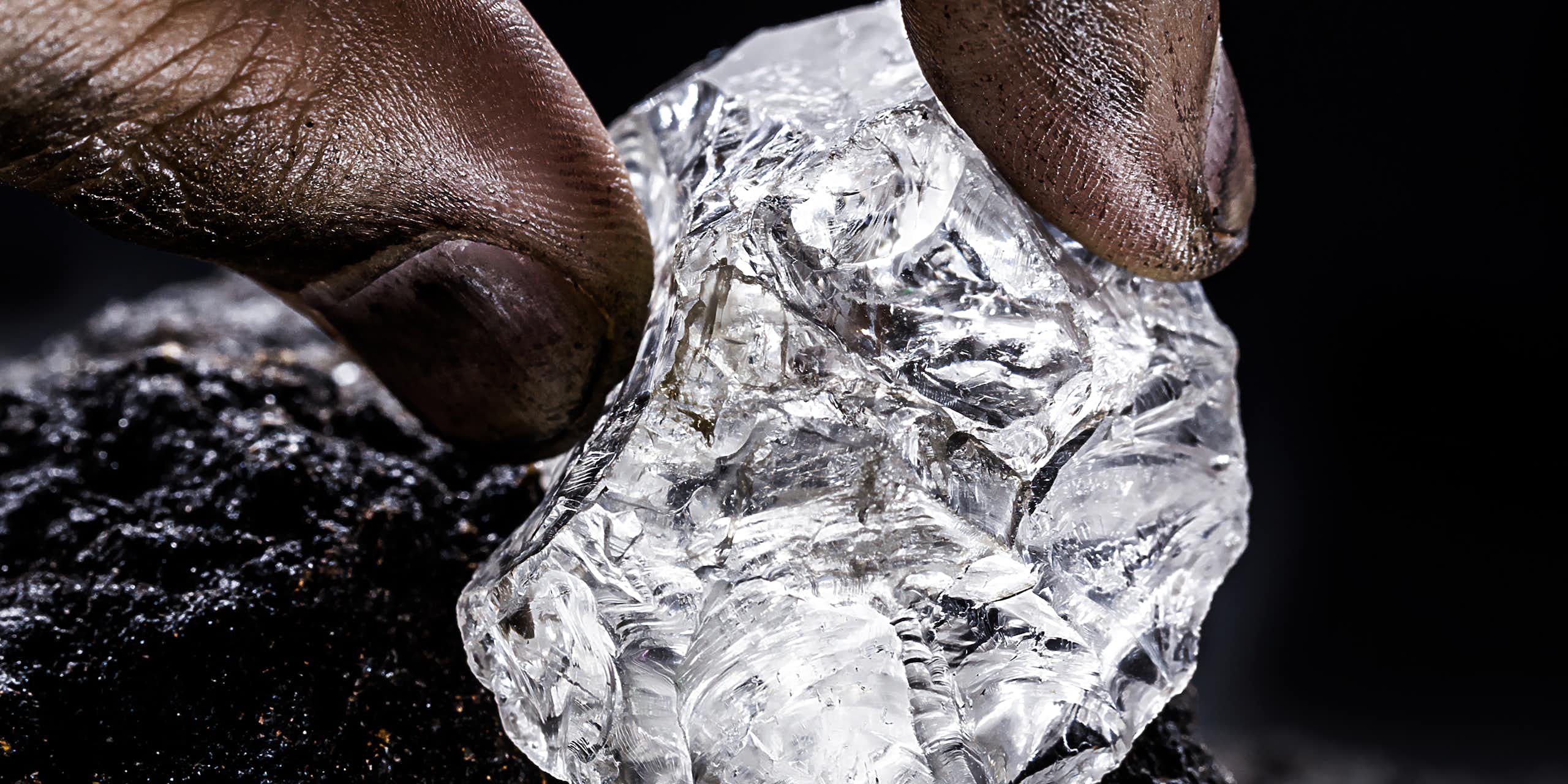 Fingers holding a lump of a shiny substance