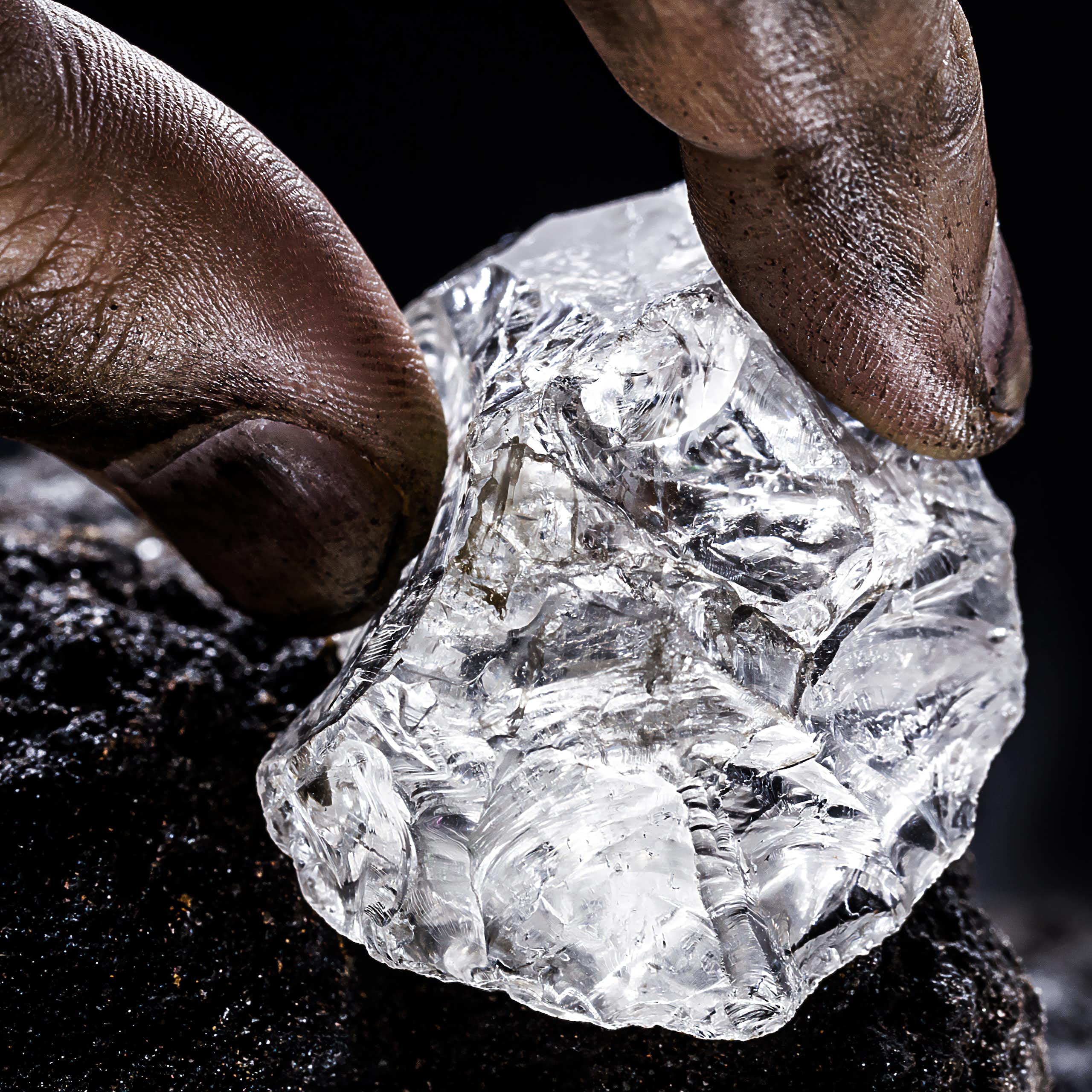 Fingers holding a lump of a shiny substance