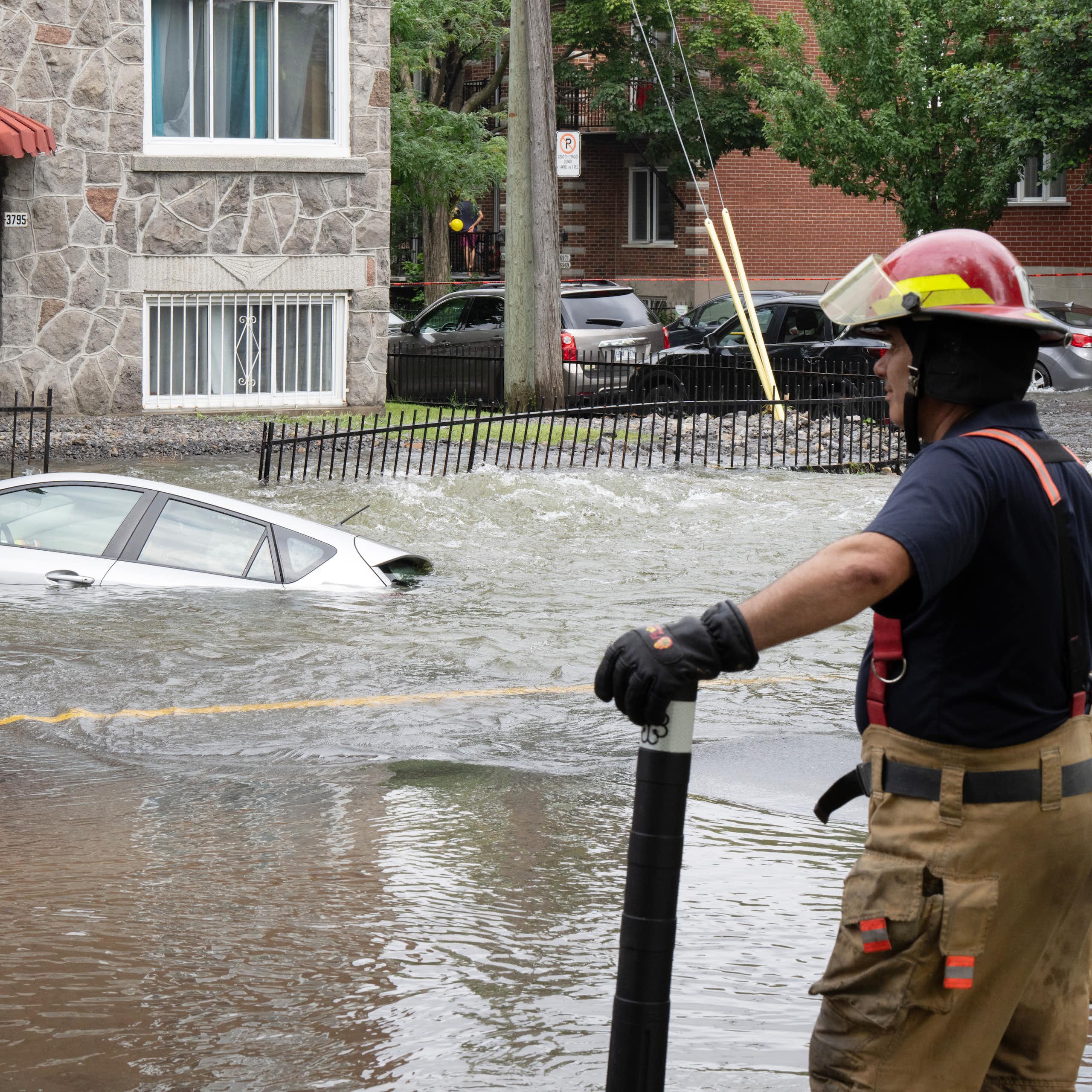 Un pompier se tient en marge d'une rue inondée
