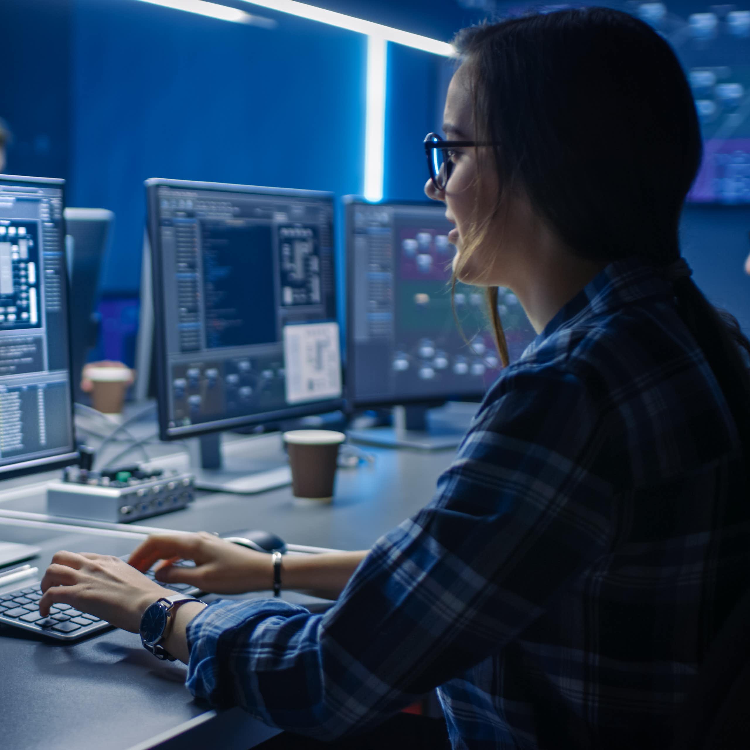 Une femme en train de coder, face à un ordinateur