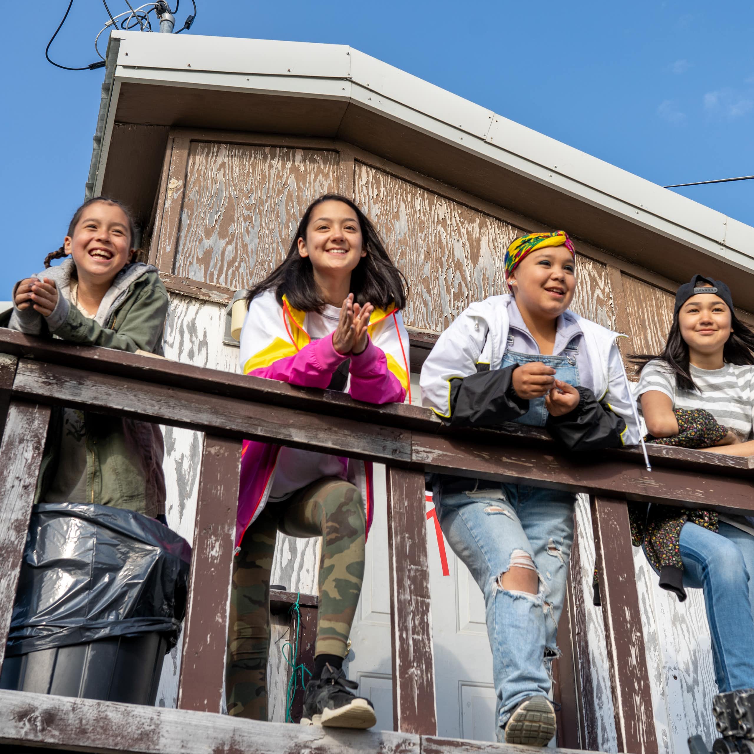 Girls standing on a porch surveying space and smiling. 