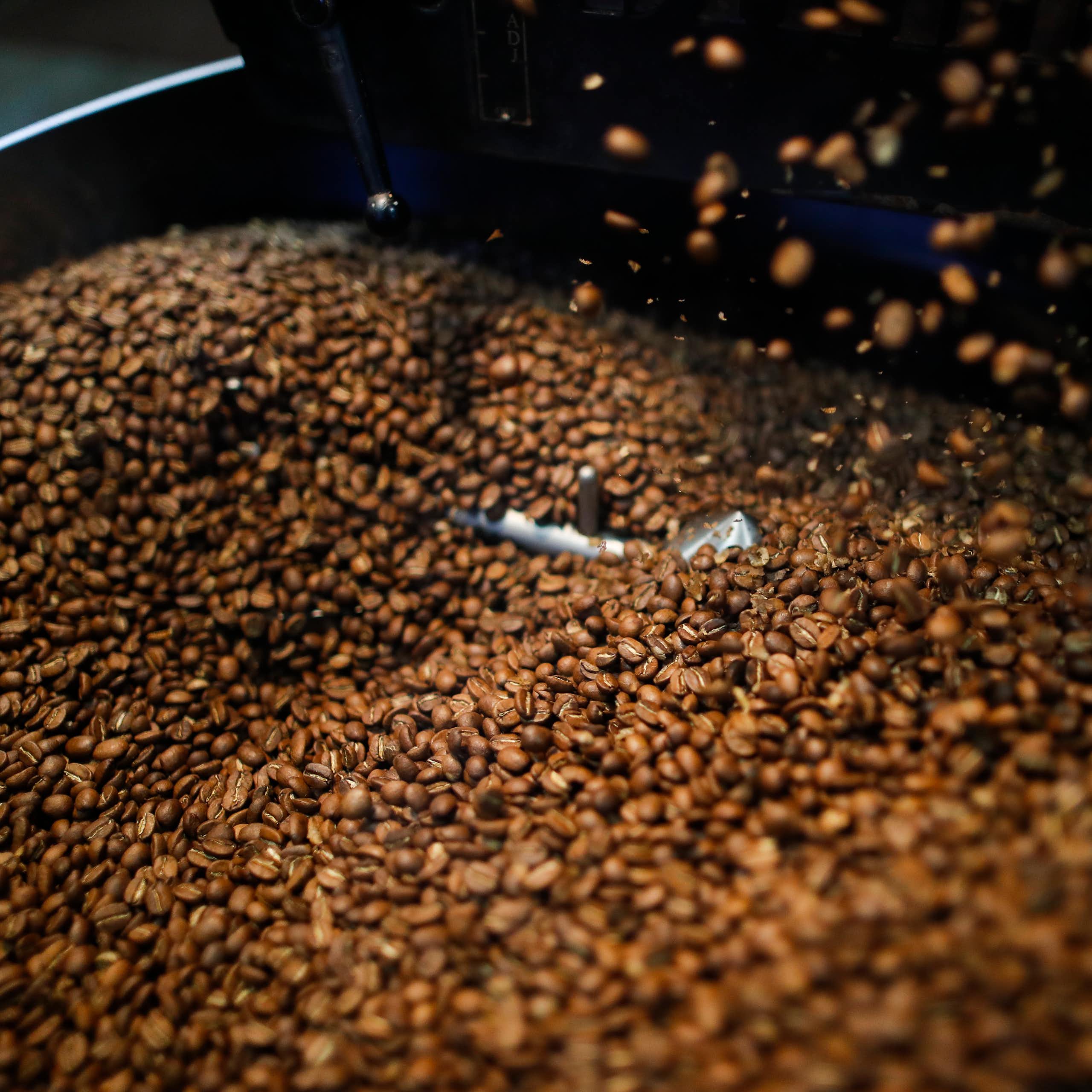 Uma grande pilha de grãos de café em uma caixa de metal.