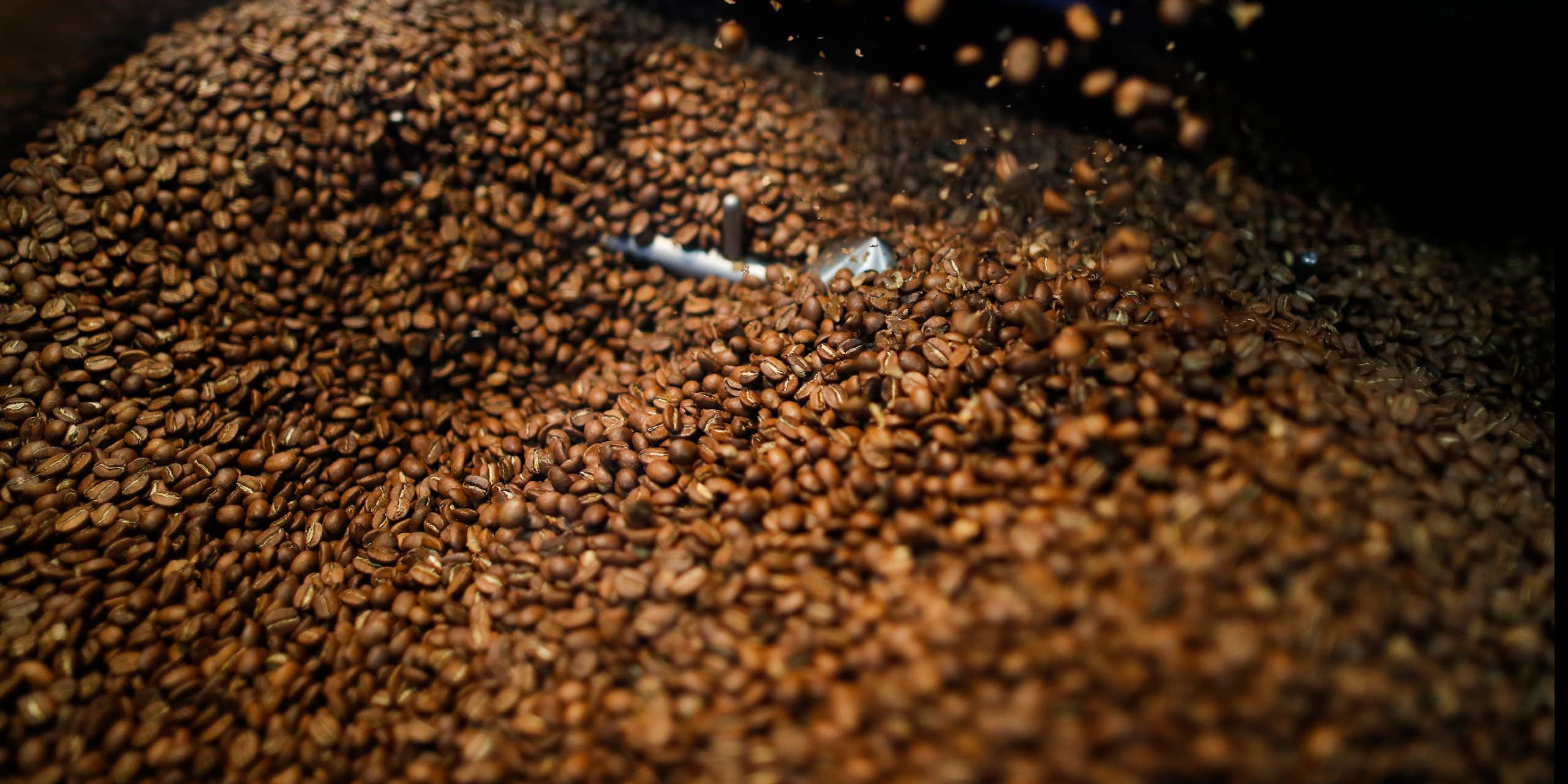 Uma grande pilha de grãos de café em uma caixa de metal.