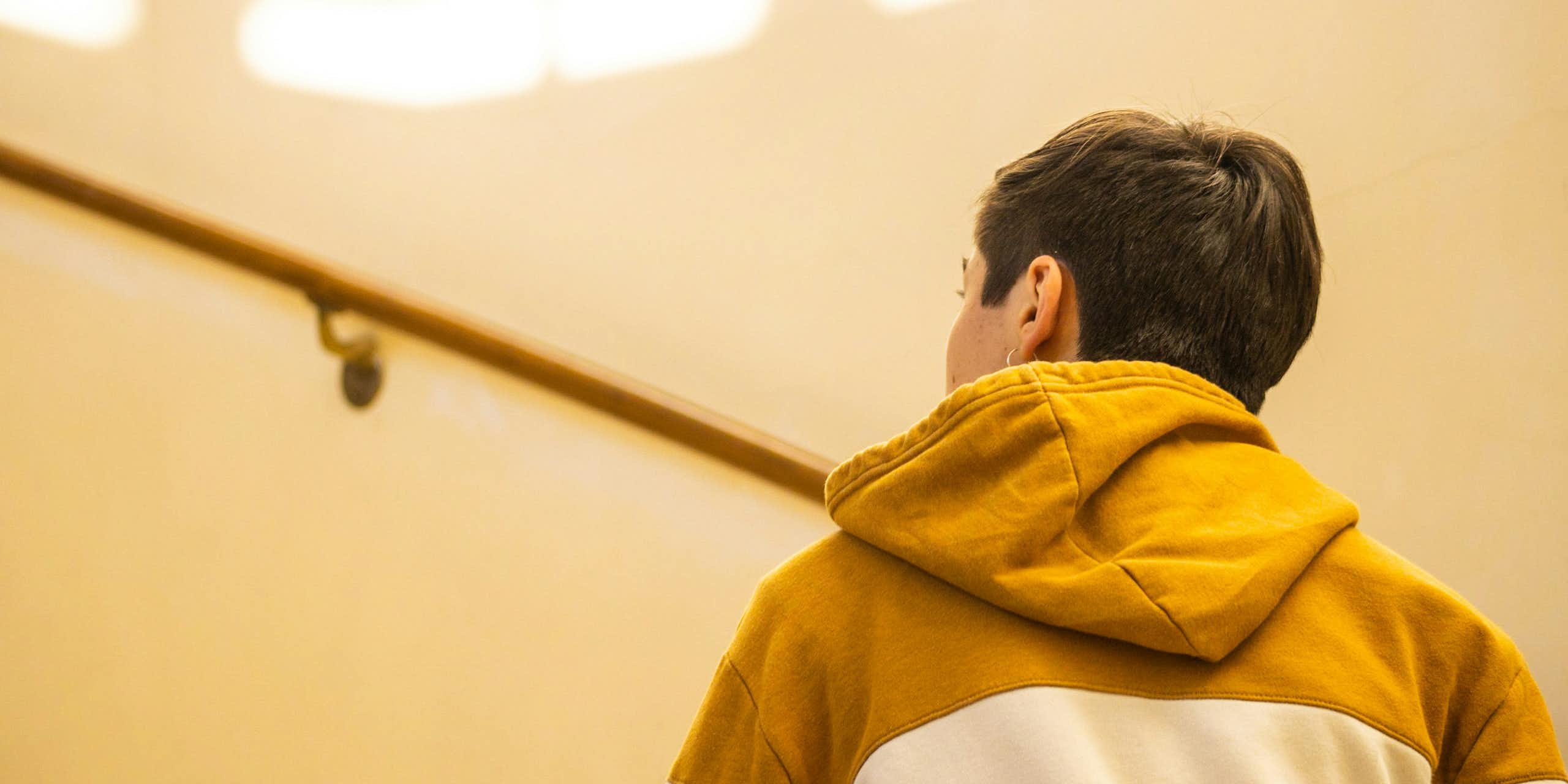 A young man in a hoodie jumper walks up a staircase.