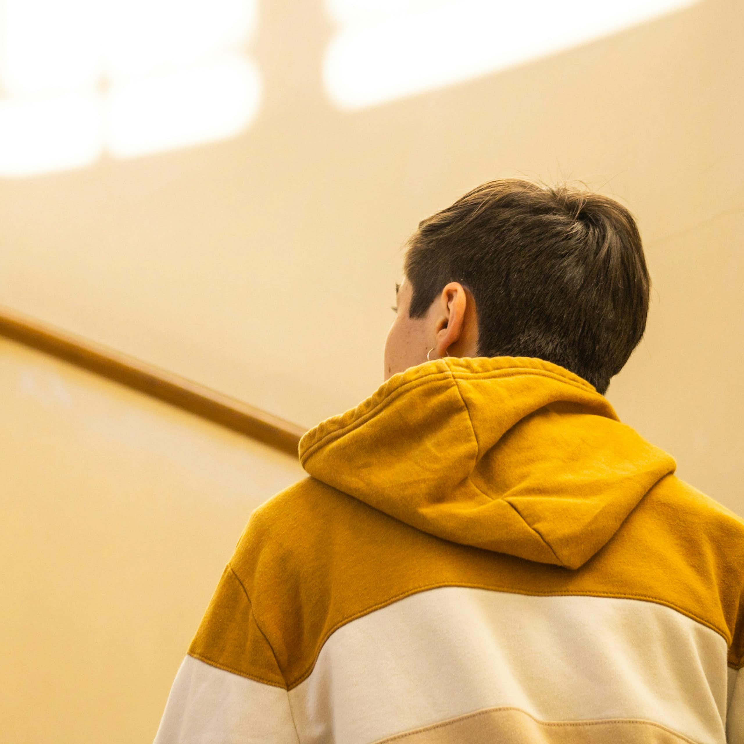 A young man in a hoodie jumper walks up a staircase.