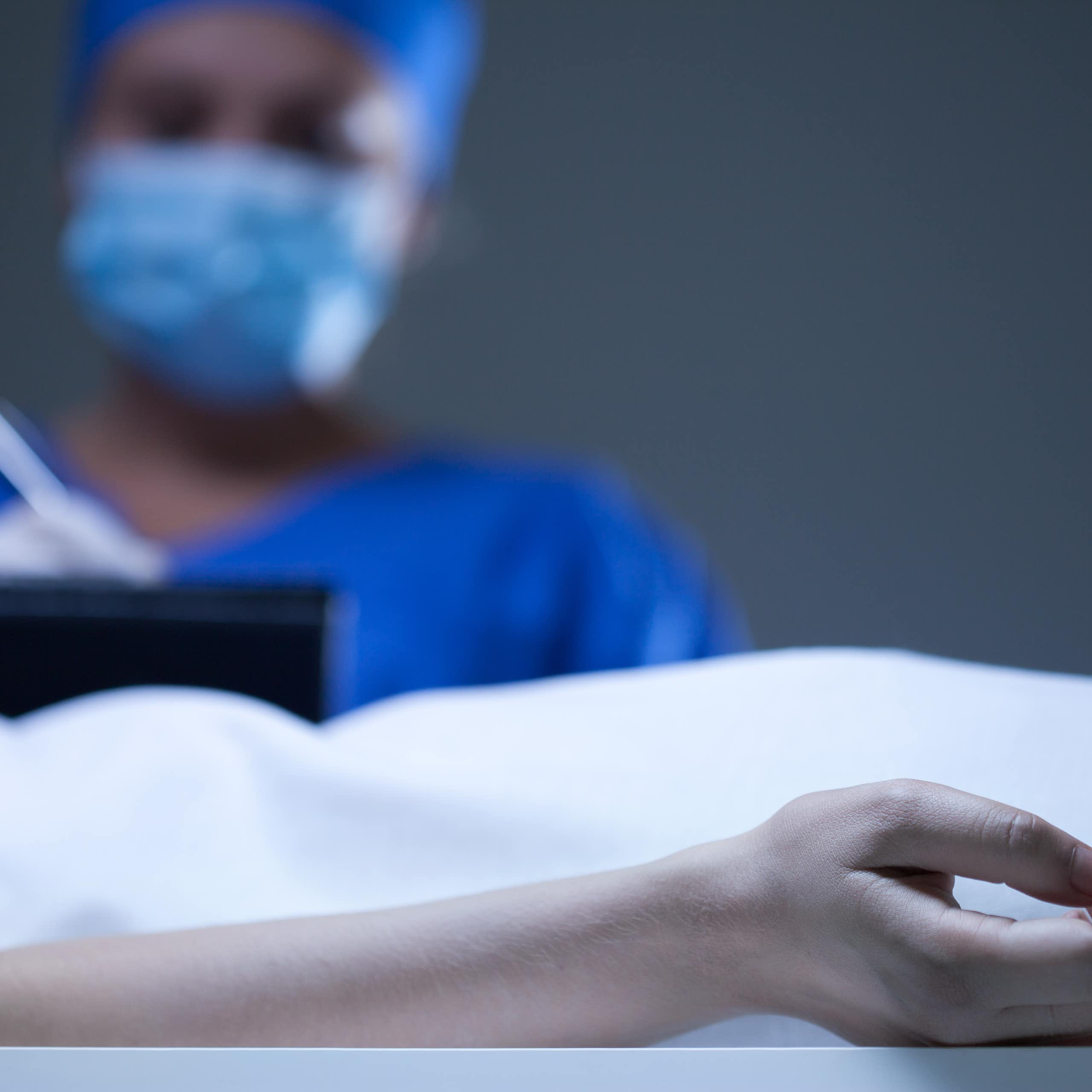 A person writes on a clip board while in an autopsy theatre.