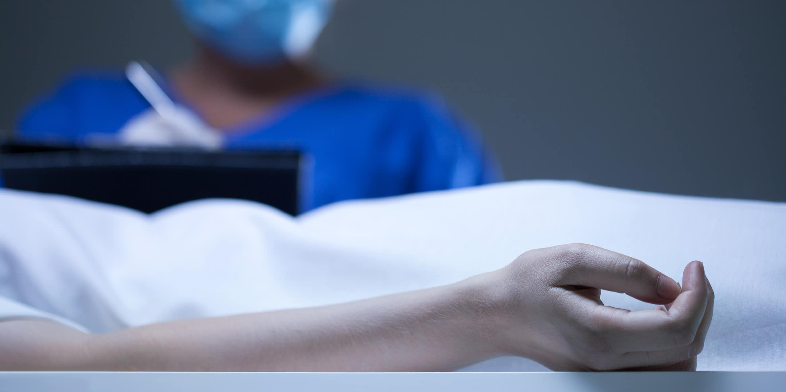 A person writes on a clip board while in an autopsy theatre.
