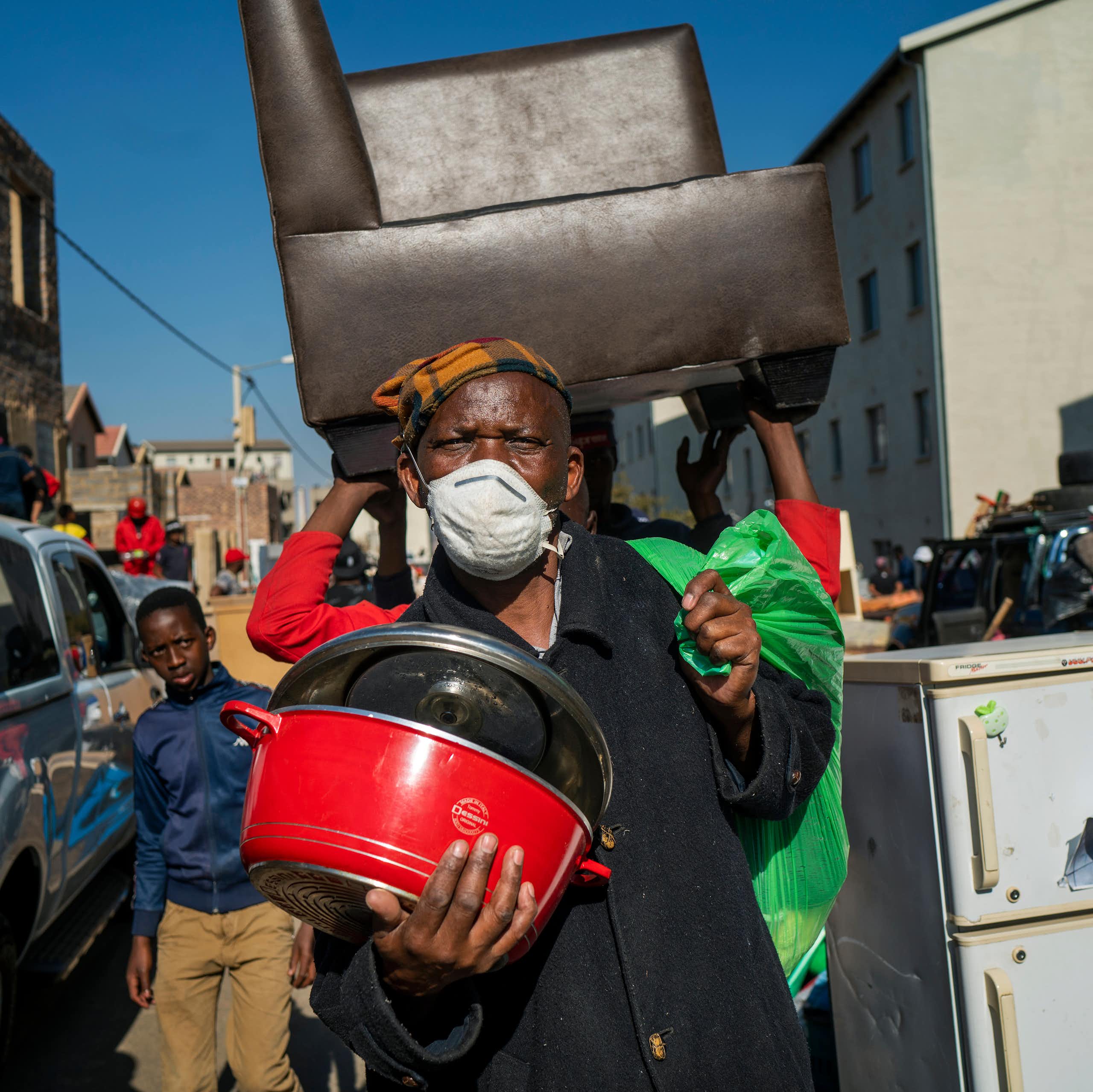 Des gens marchent dans la rue en transportant leurs biens.