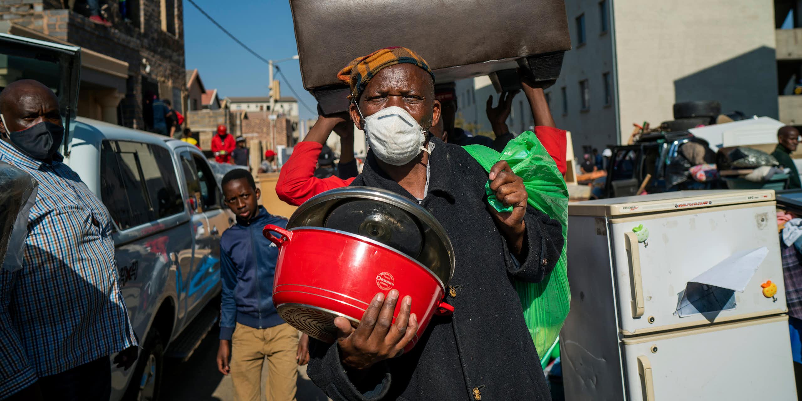 Des gens marchent dans la rue en transportant leurs biens.