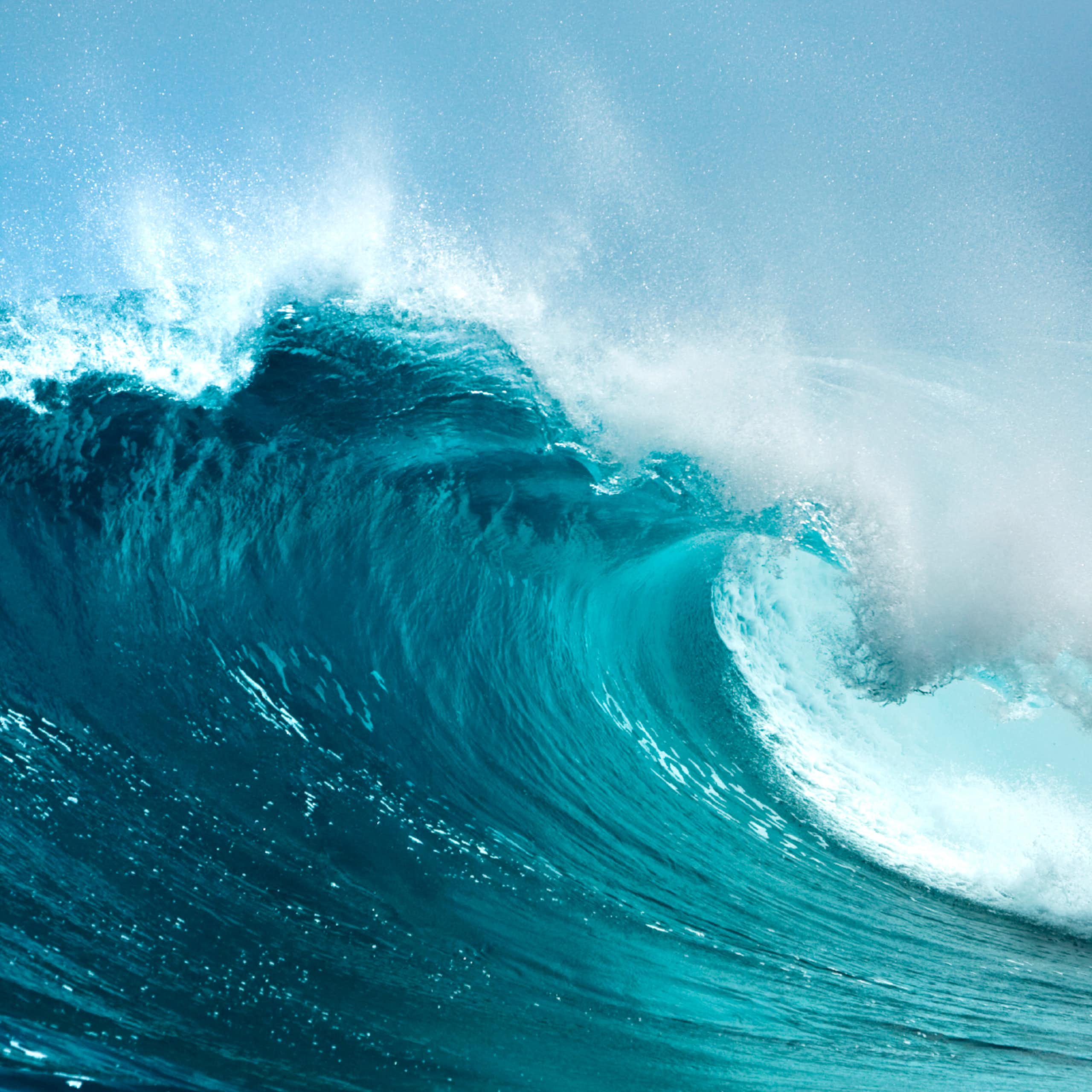 big blue wave crashing, white sea spray, blue sky