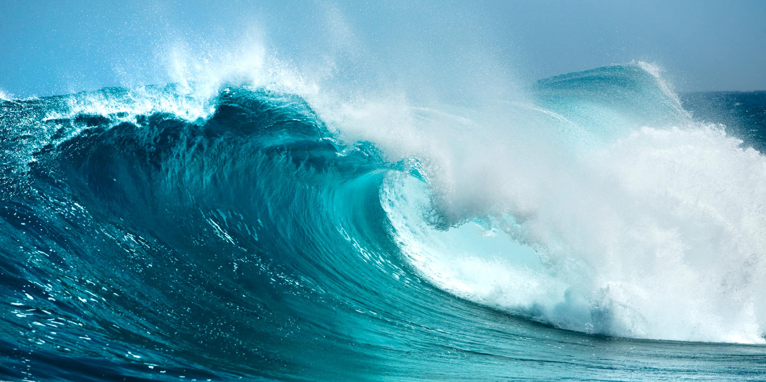 big blue wave crashing, white sea spray, blue sky