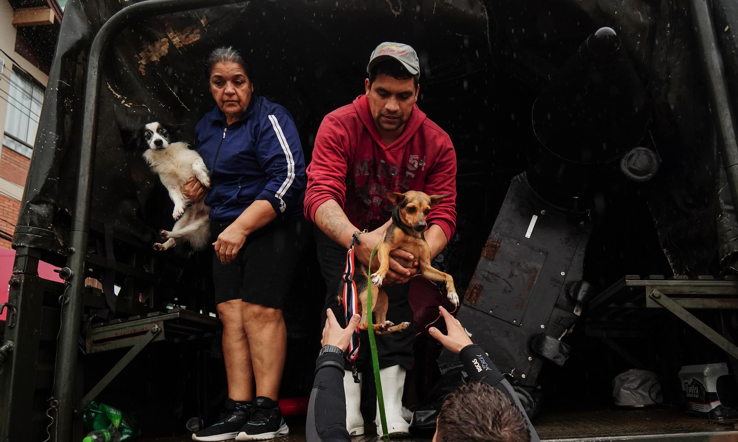 People and their pets evacuate a flooded area after heavy rain in Sao Sebastiao do Cai, Rio Grande do Sul state