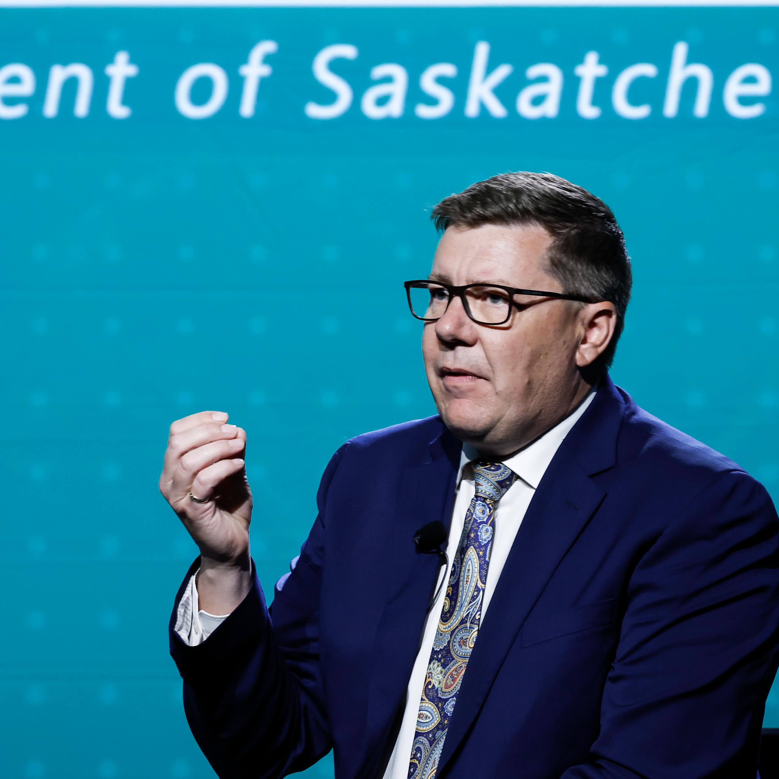 A man in a suit speaking at a podium.