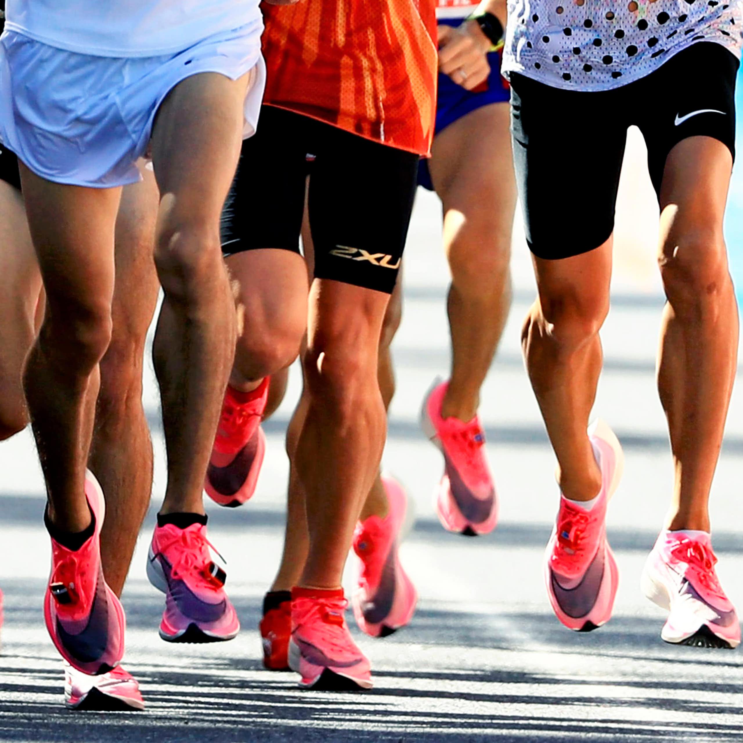 Action shot of a large group of people running, most wearing white and pink Nike shoes.