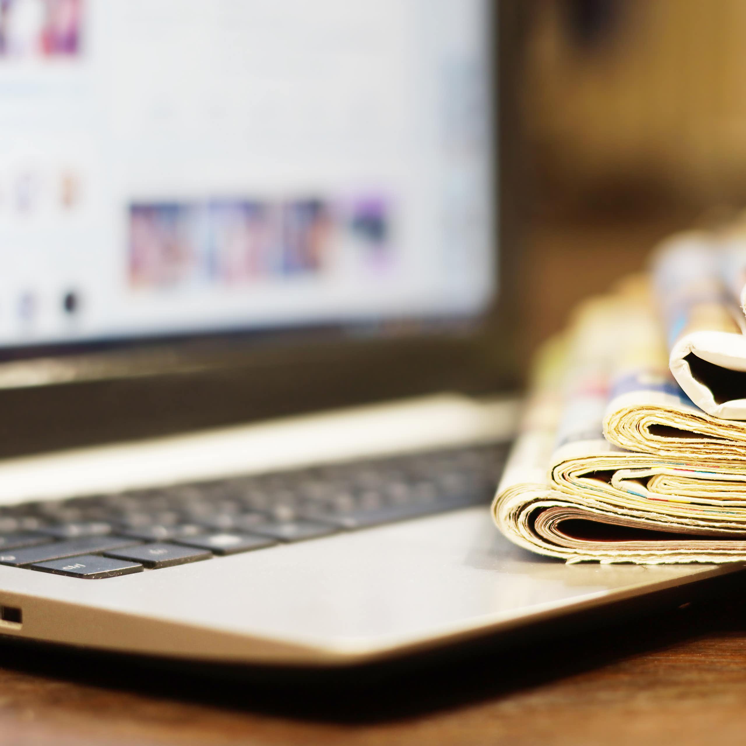 Une pile de journaux repose sur un ordinateur portable