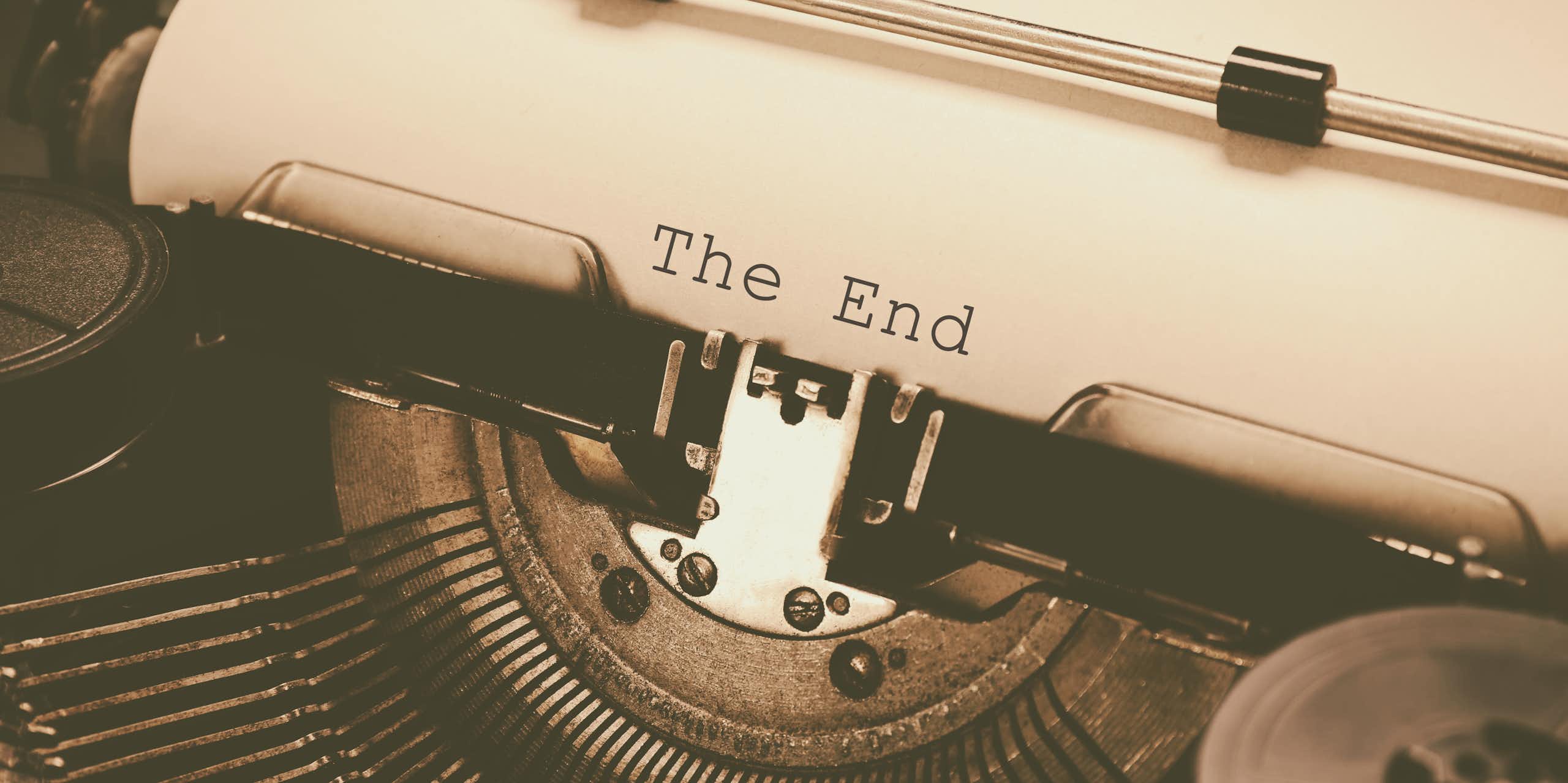 Uma velha máquina de datilografar com uma folha de papel onde se lê as palavras "The End" (fim)