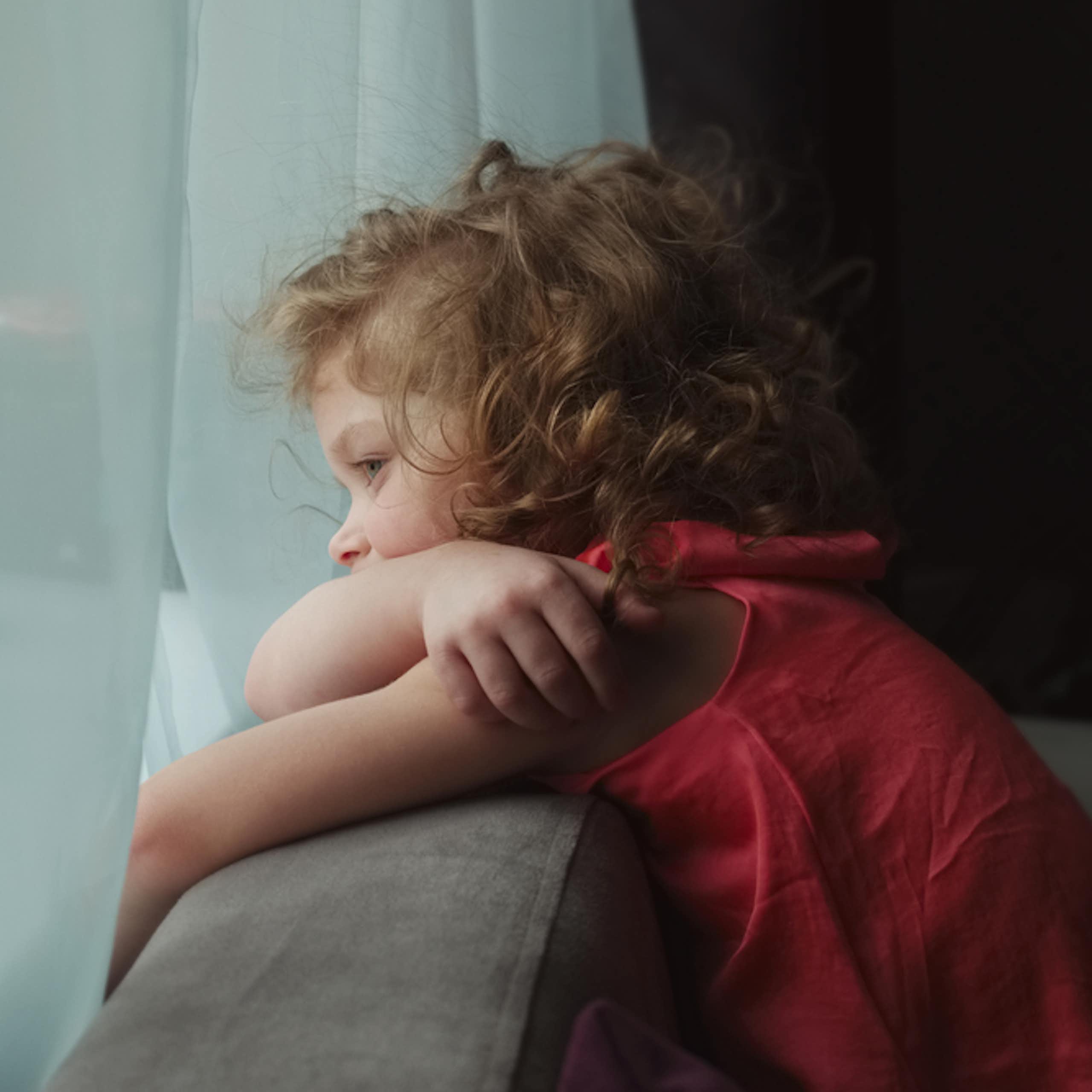 Petite fille qui s'ennuie devant une fenêtre