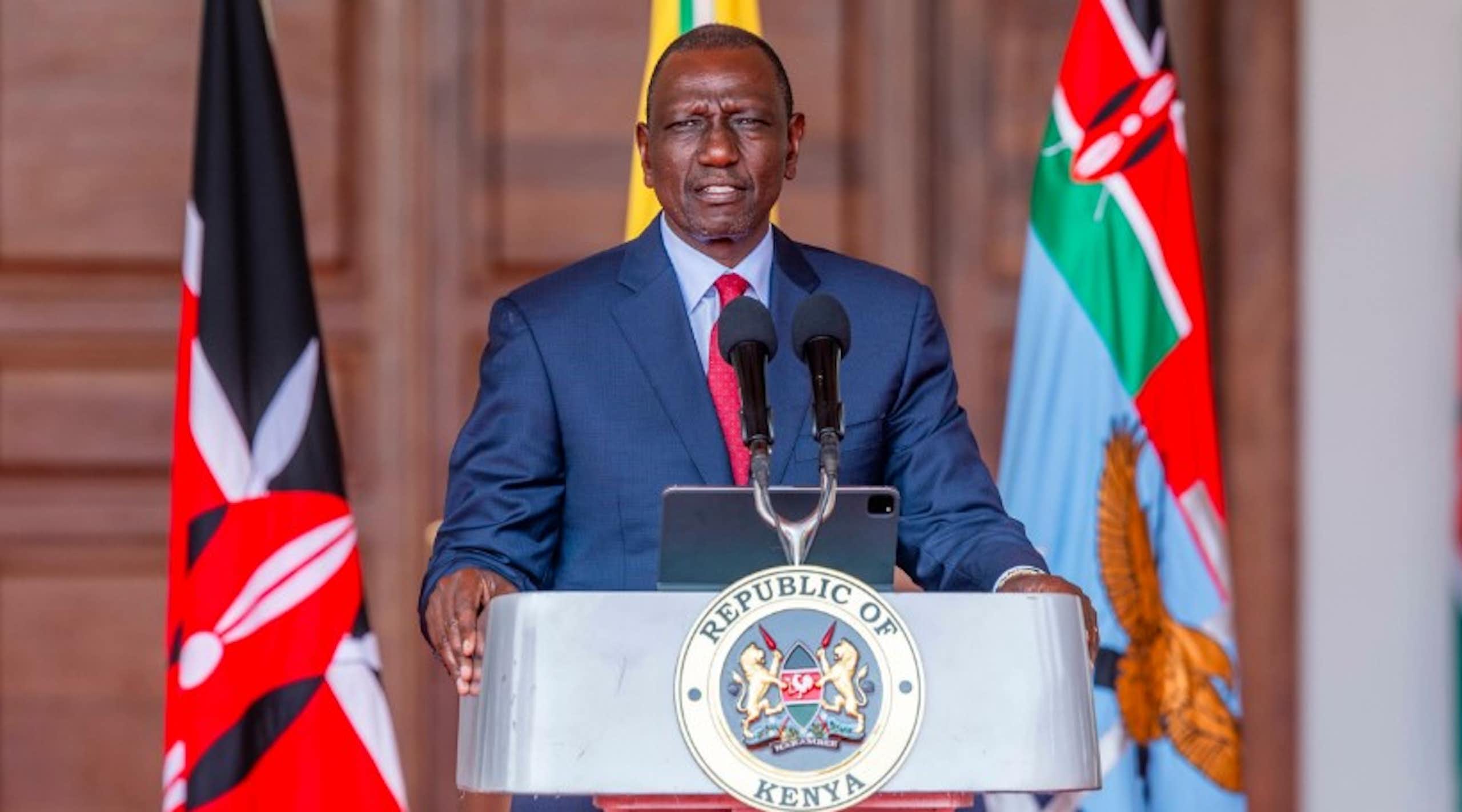 Man in suit and tie standing at a podium marked 'Republic of Kenya'