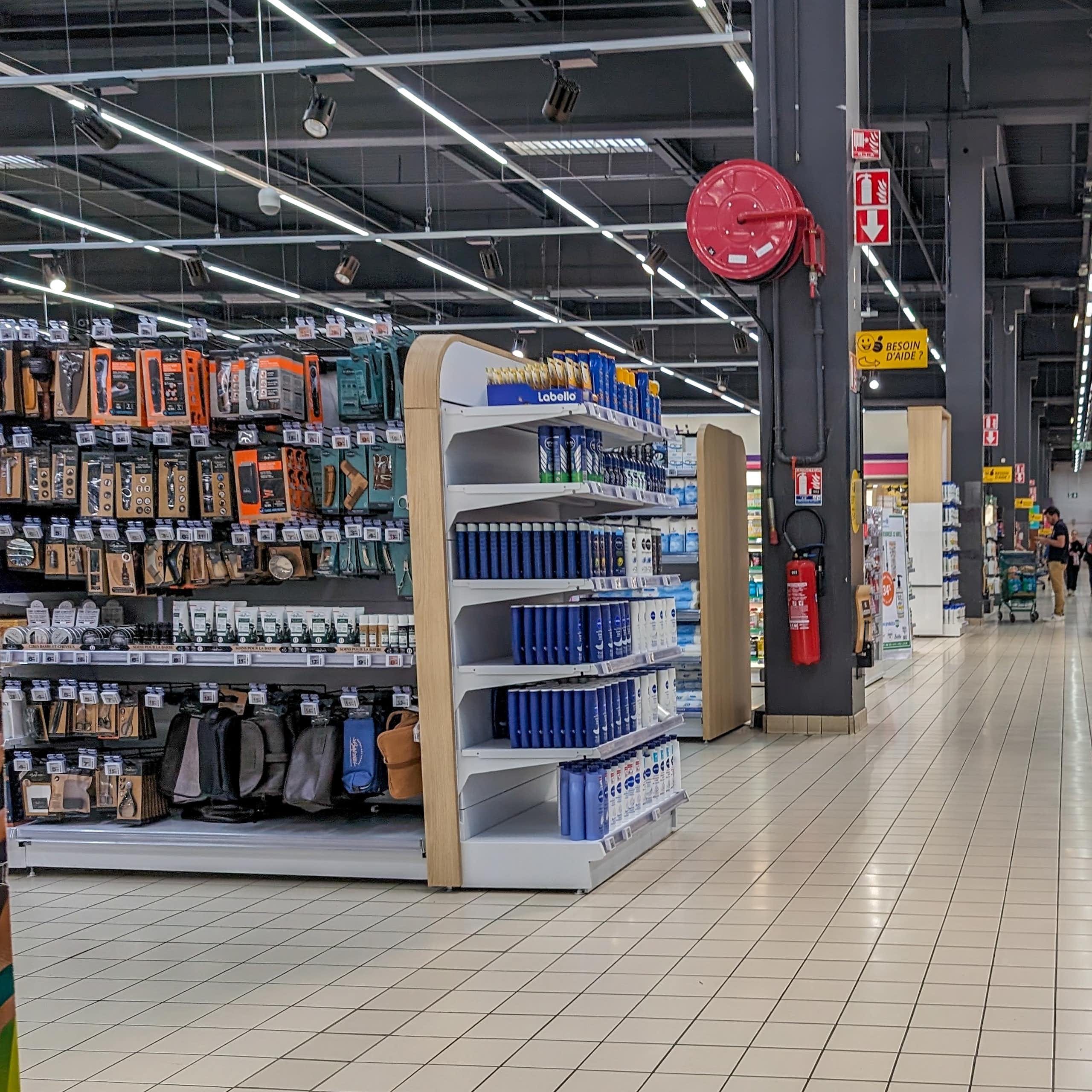 rayons d'un hypermarché avec au loin une personne qui pousse un chariot dans un magasin vide