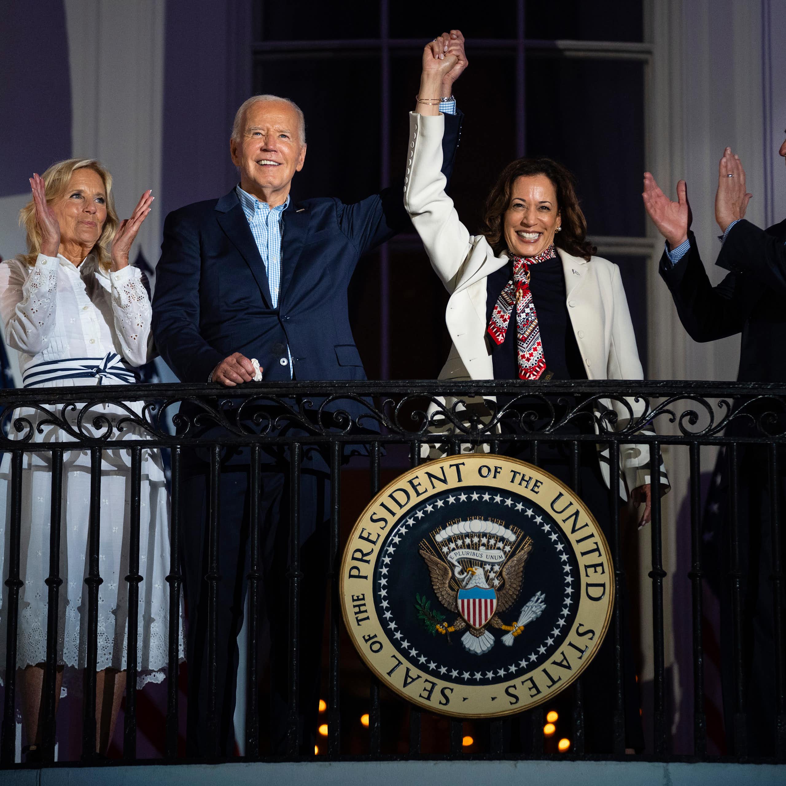 Kamala Harris waves from a balcony, with her hand held aloft by Joe Biden