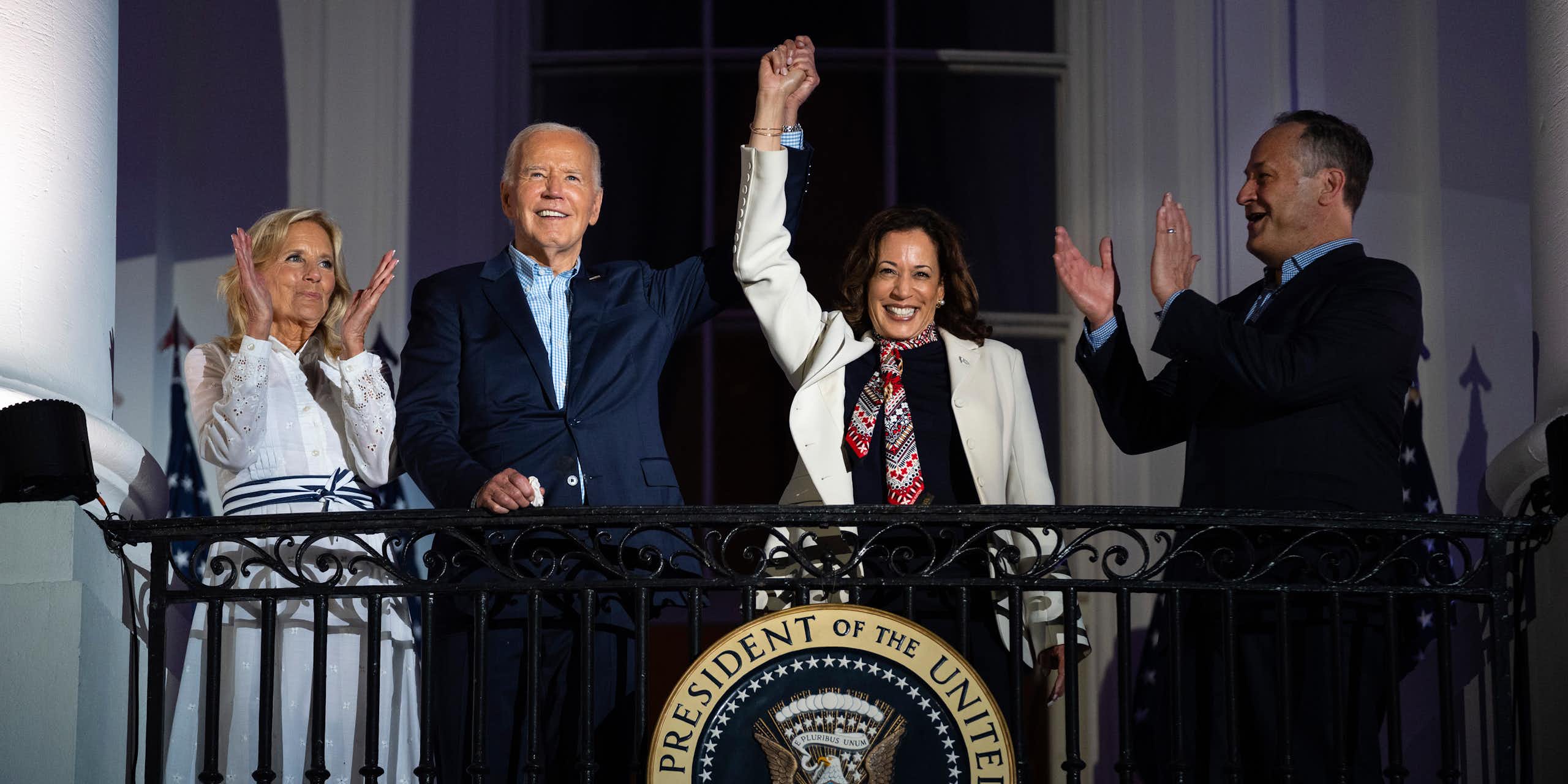 Kamala Harris waves from a balcony, with her hand held aloft by Joe Biden