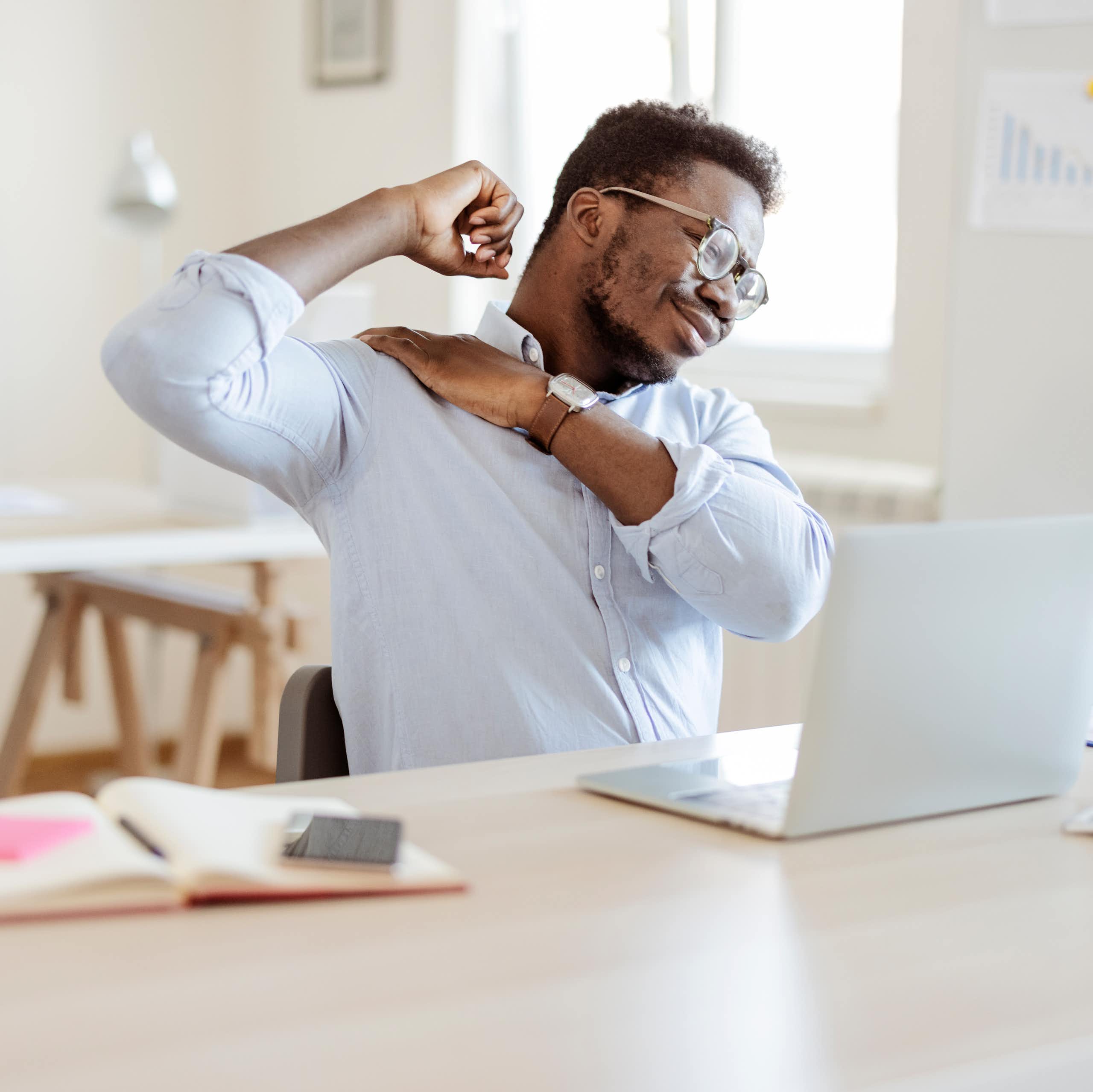 Man with back pain stretches at desk
