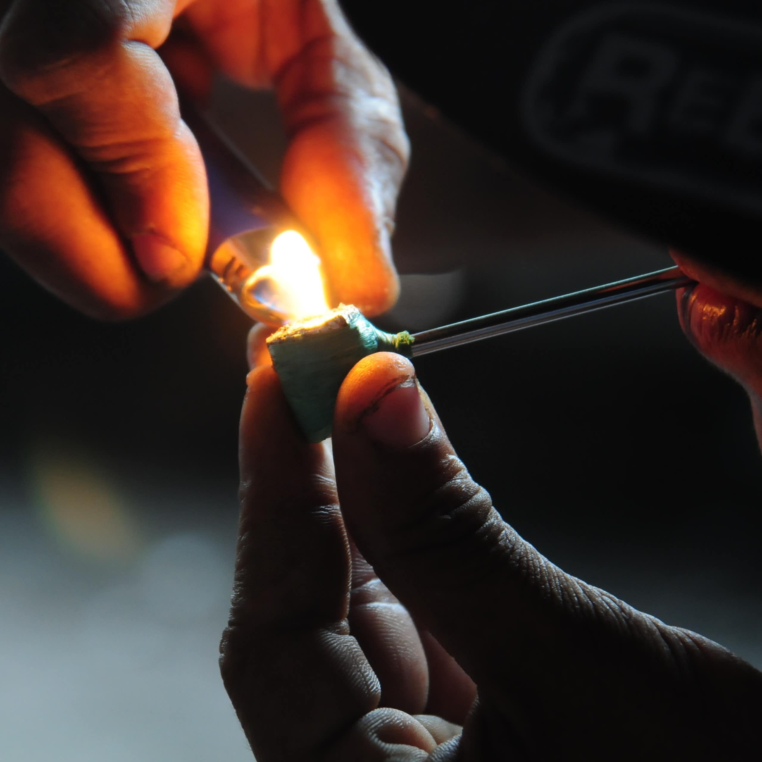 two hands are seen lighting up a pipe