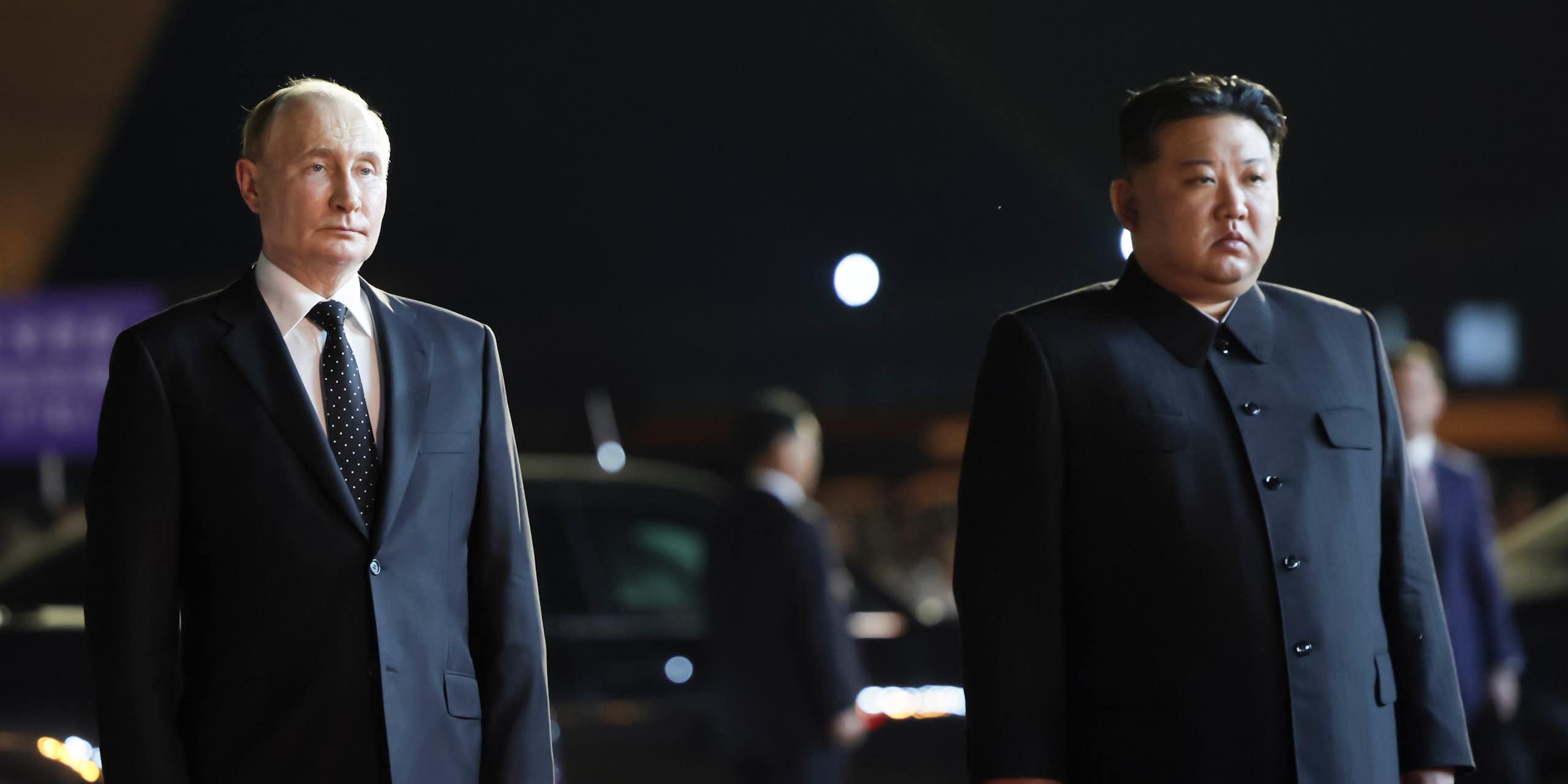 Two men, one a balding white man and another a rotund Asian man, stand side by side on an airport tarmac.