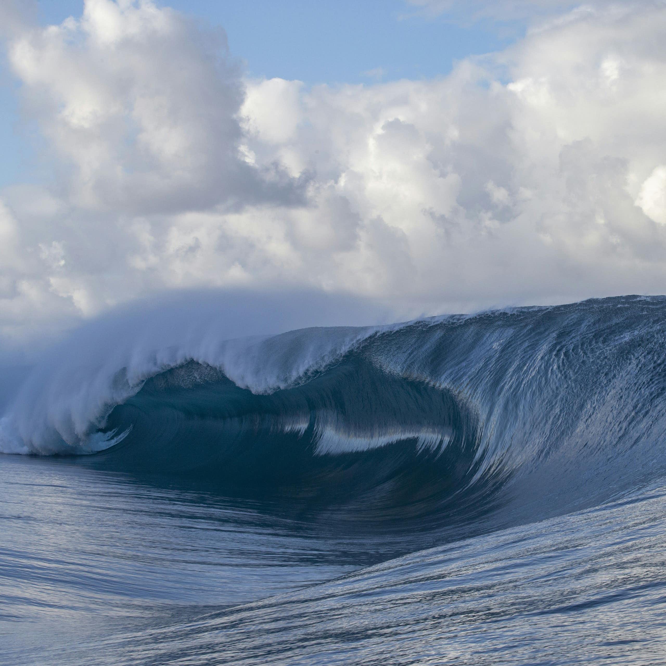 Surfers cresting breaking wave at Teahupo'o