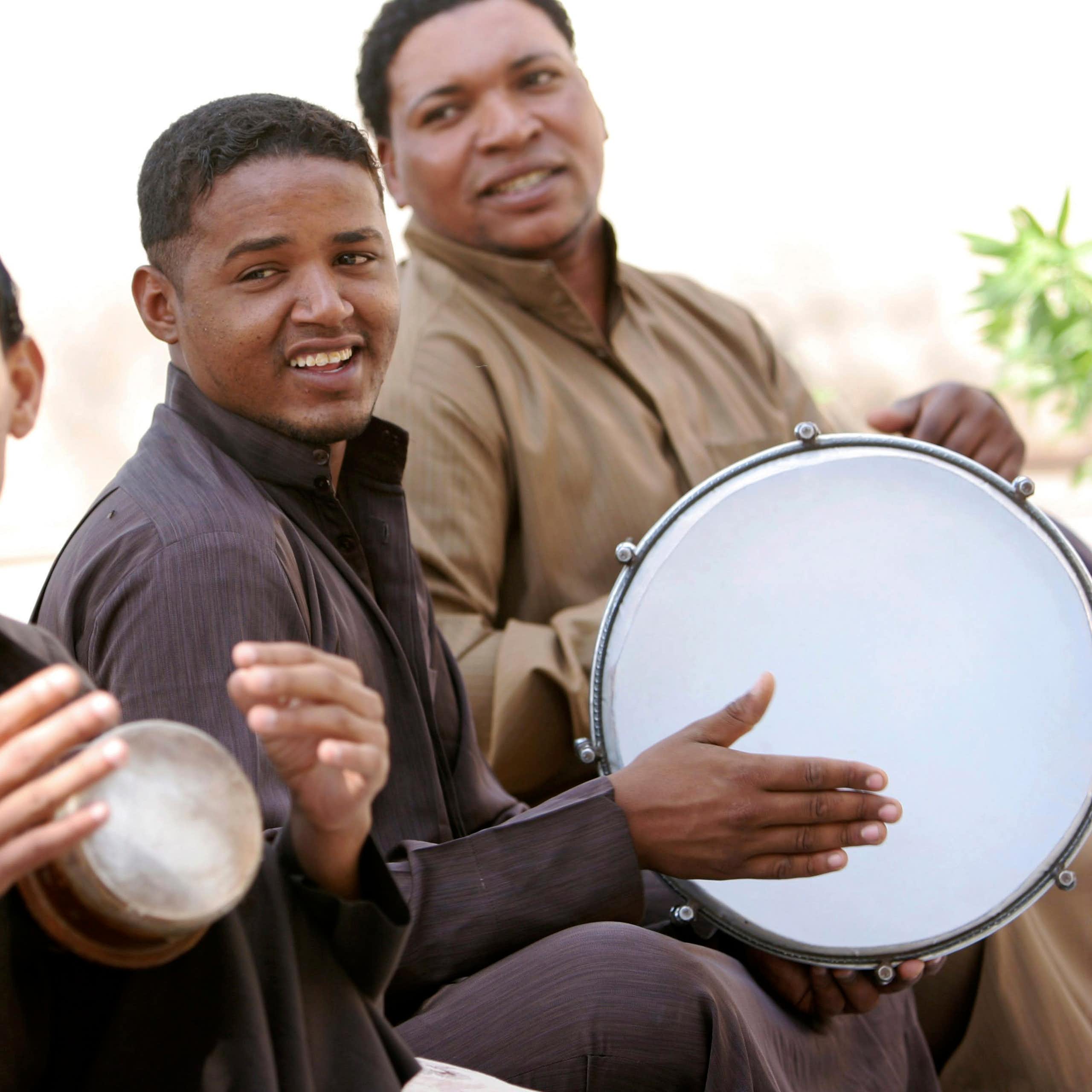 Men sit in a row playing drums