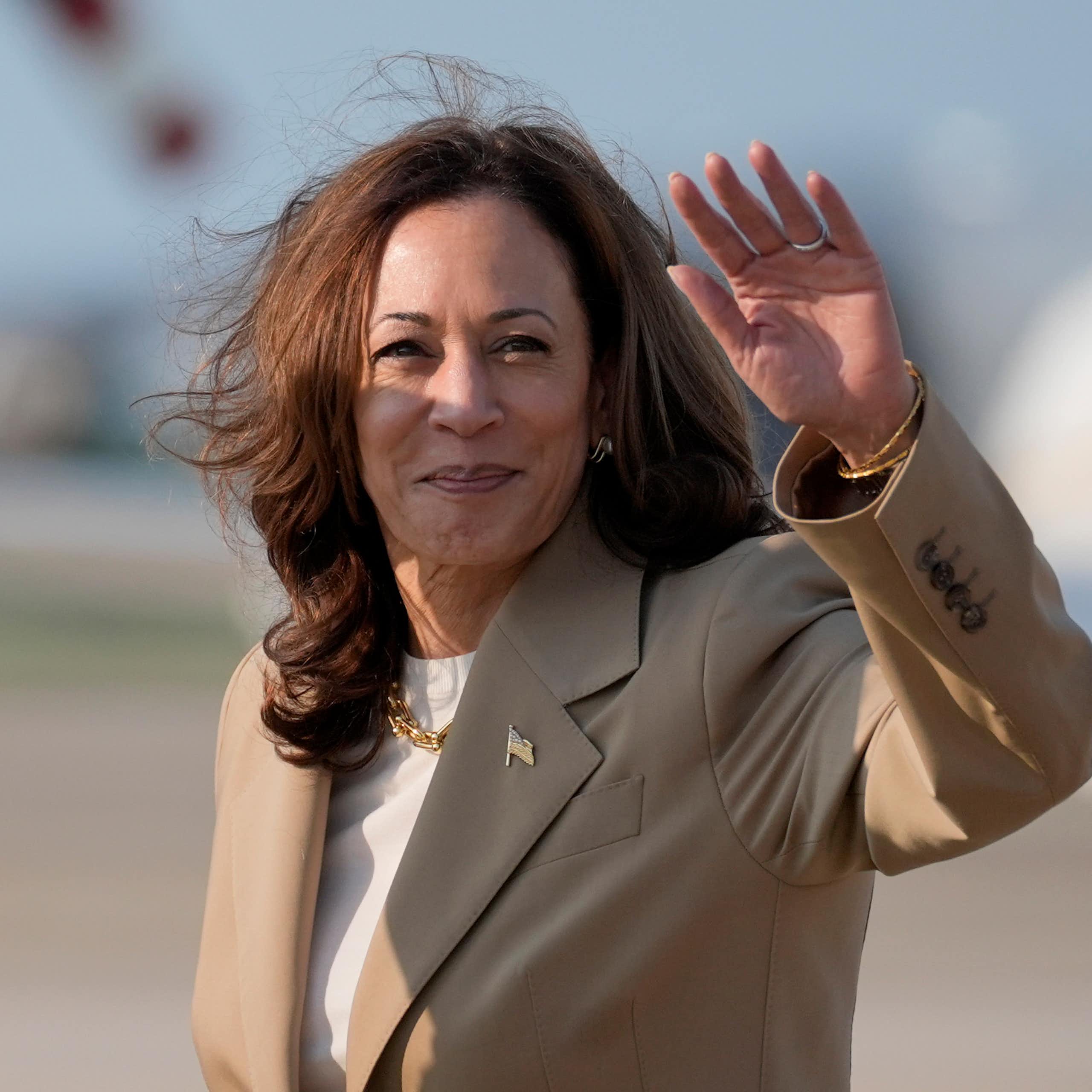 Kamala Harris debout devant un avion, saluant de la main gauche