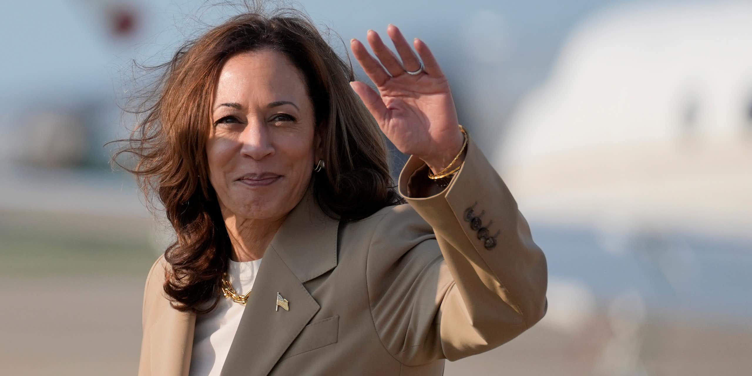 Kamala Harris debout devant un avion, saluant de la main gauche