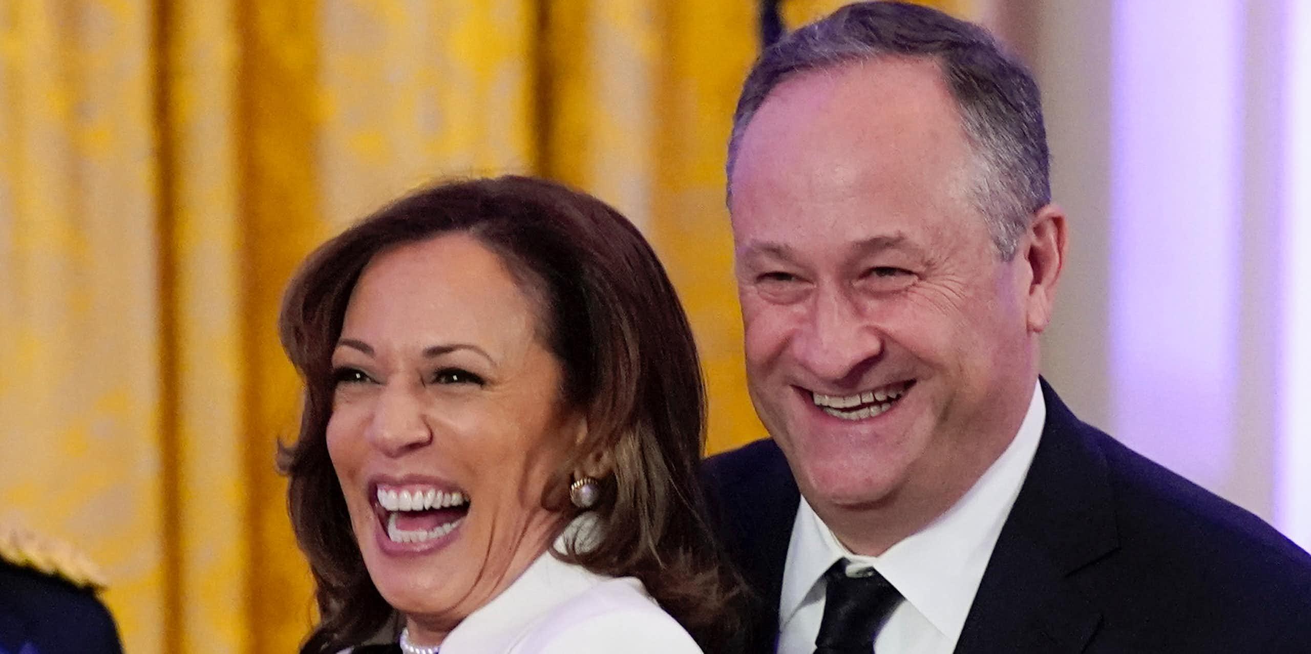 A vice-presidente dos EUA Kamala Harris sorrindo ao lado de seu marido, um homem branco de terno