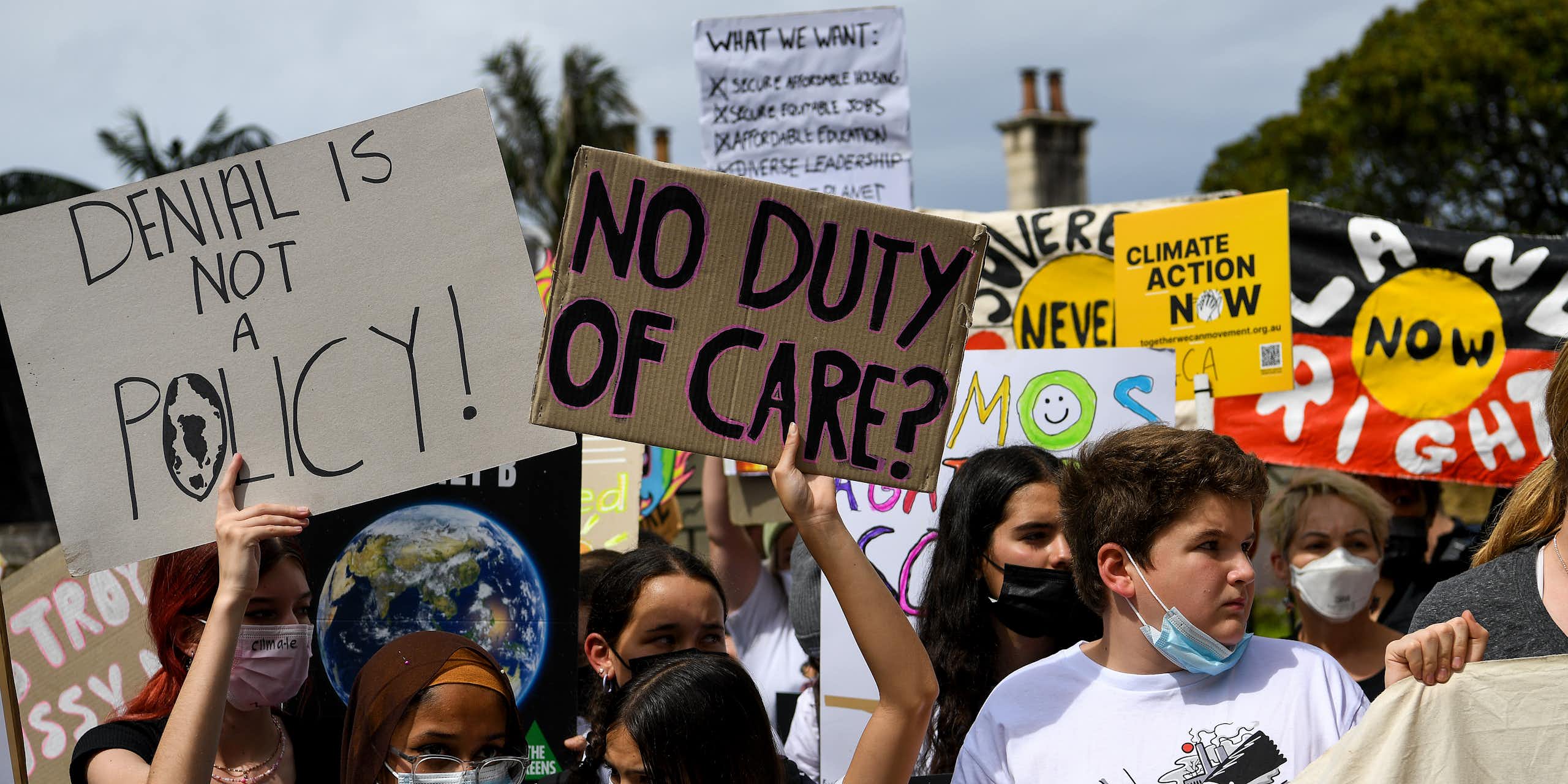 A group of young people protesting outside holding signs