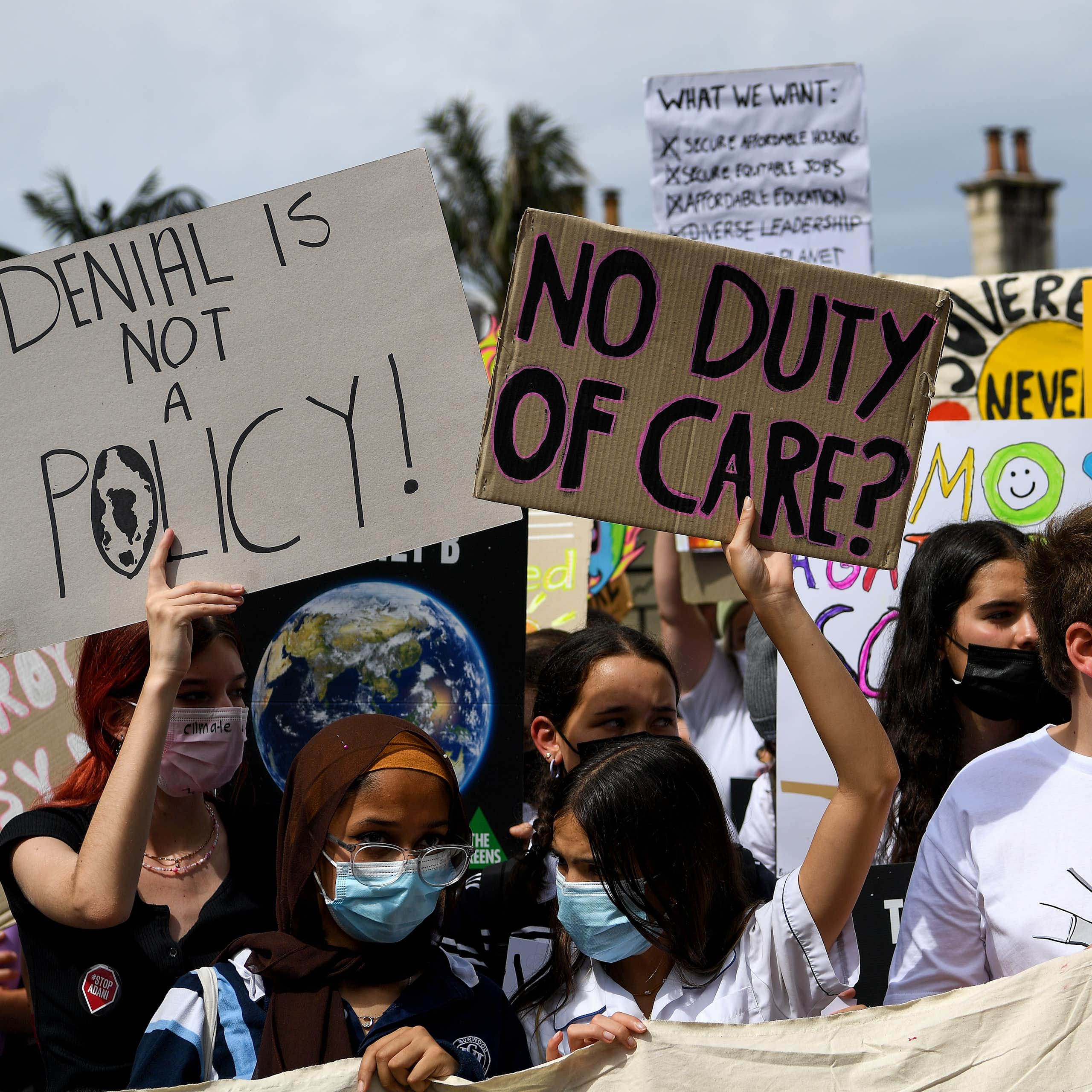A group of young people protesting outside holding signs