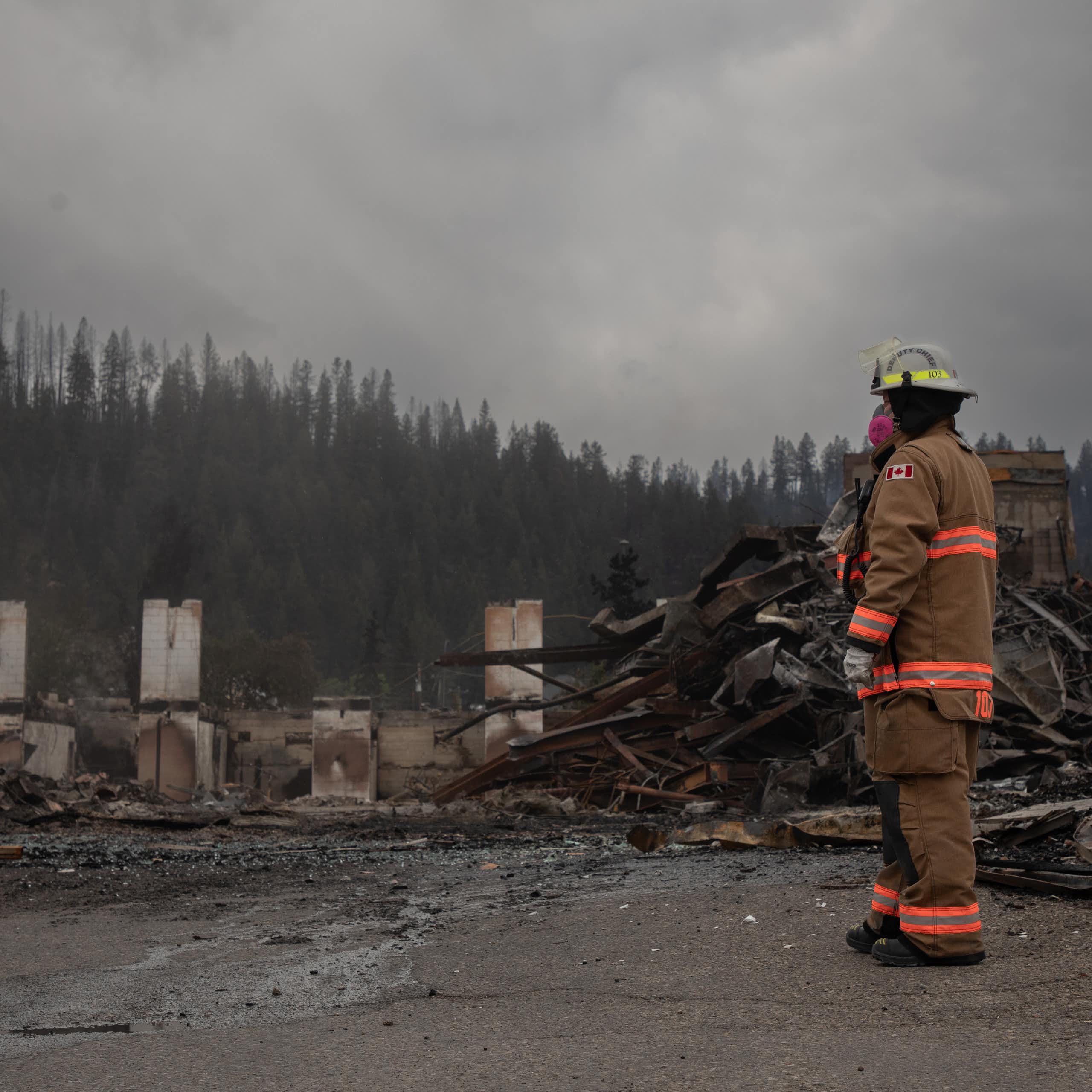 A firefighter stands by the burned wreck of a building.