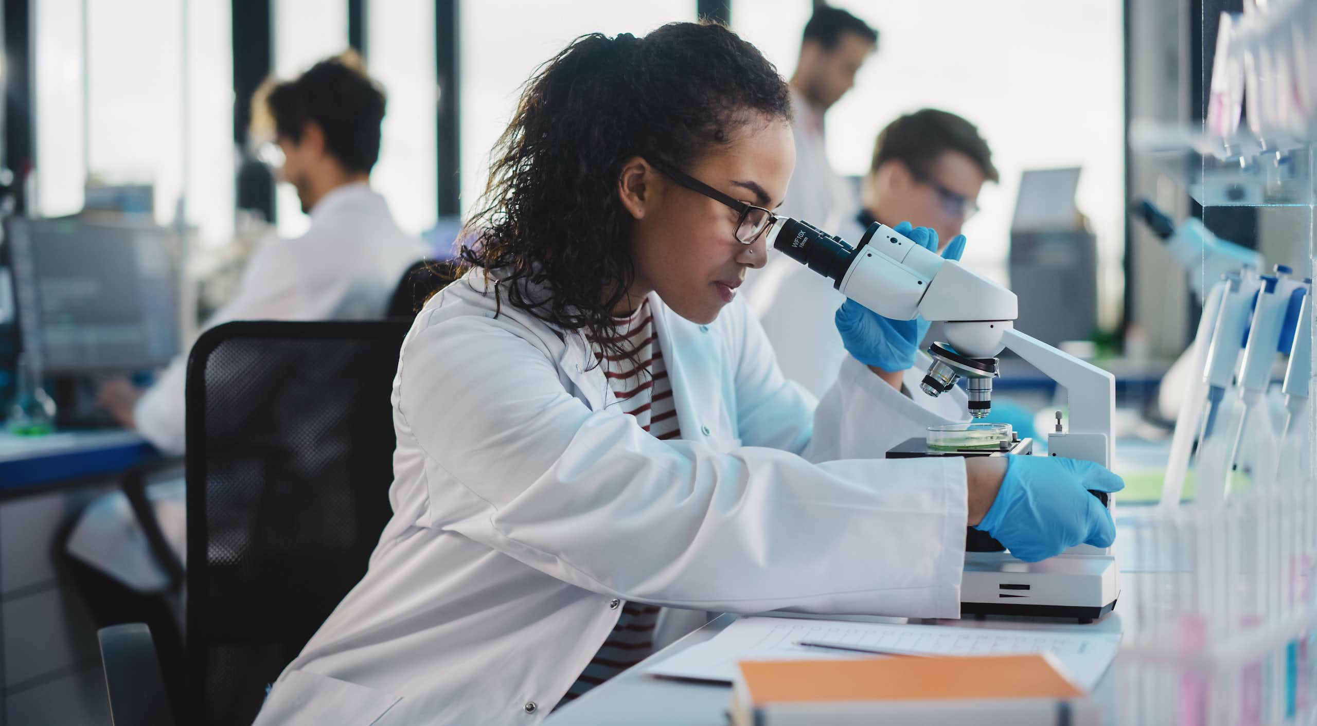 male and female scientists working in lab at microscopes