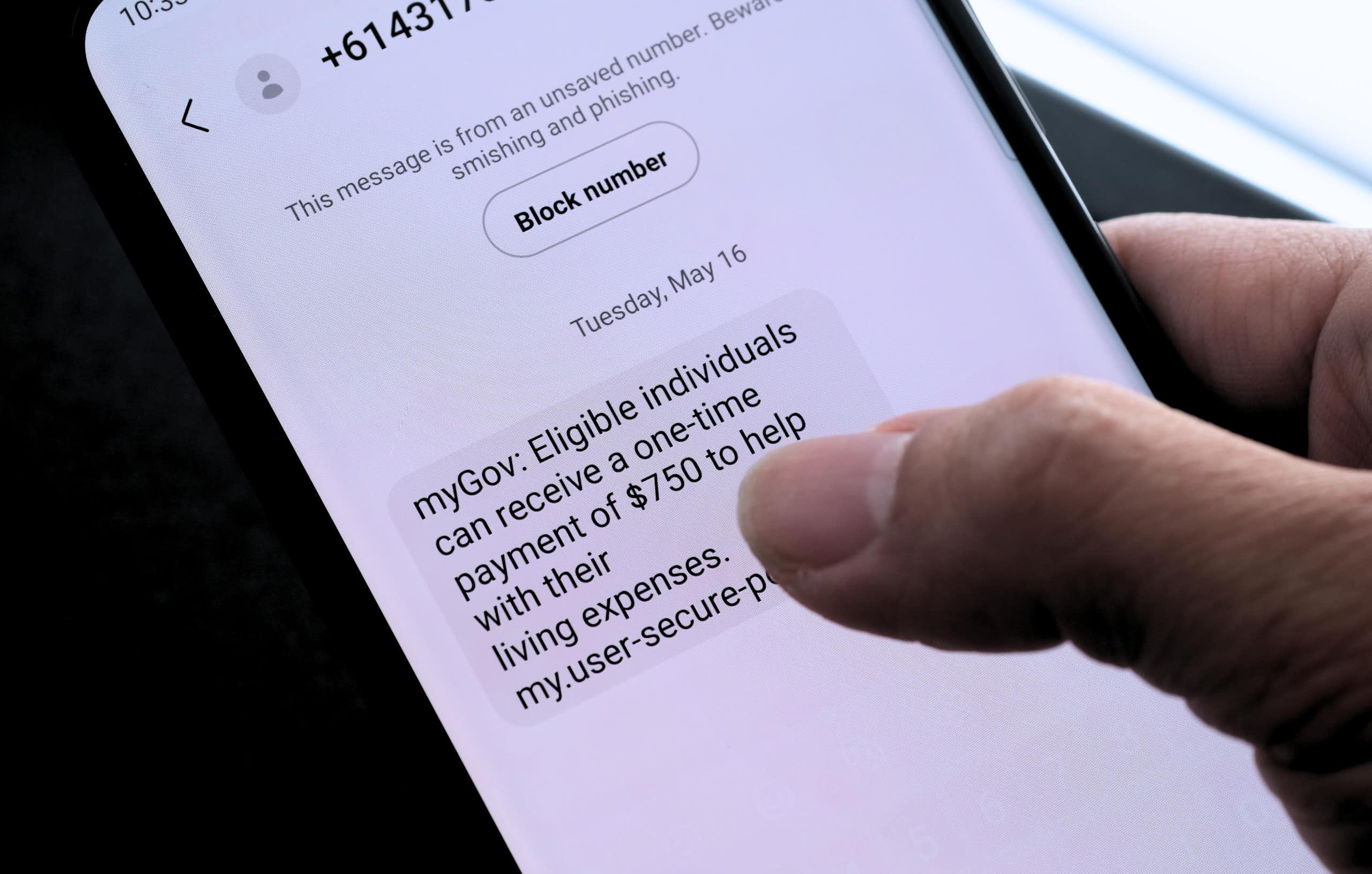 A person reading a text that advises them of a fake myGov payment.