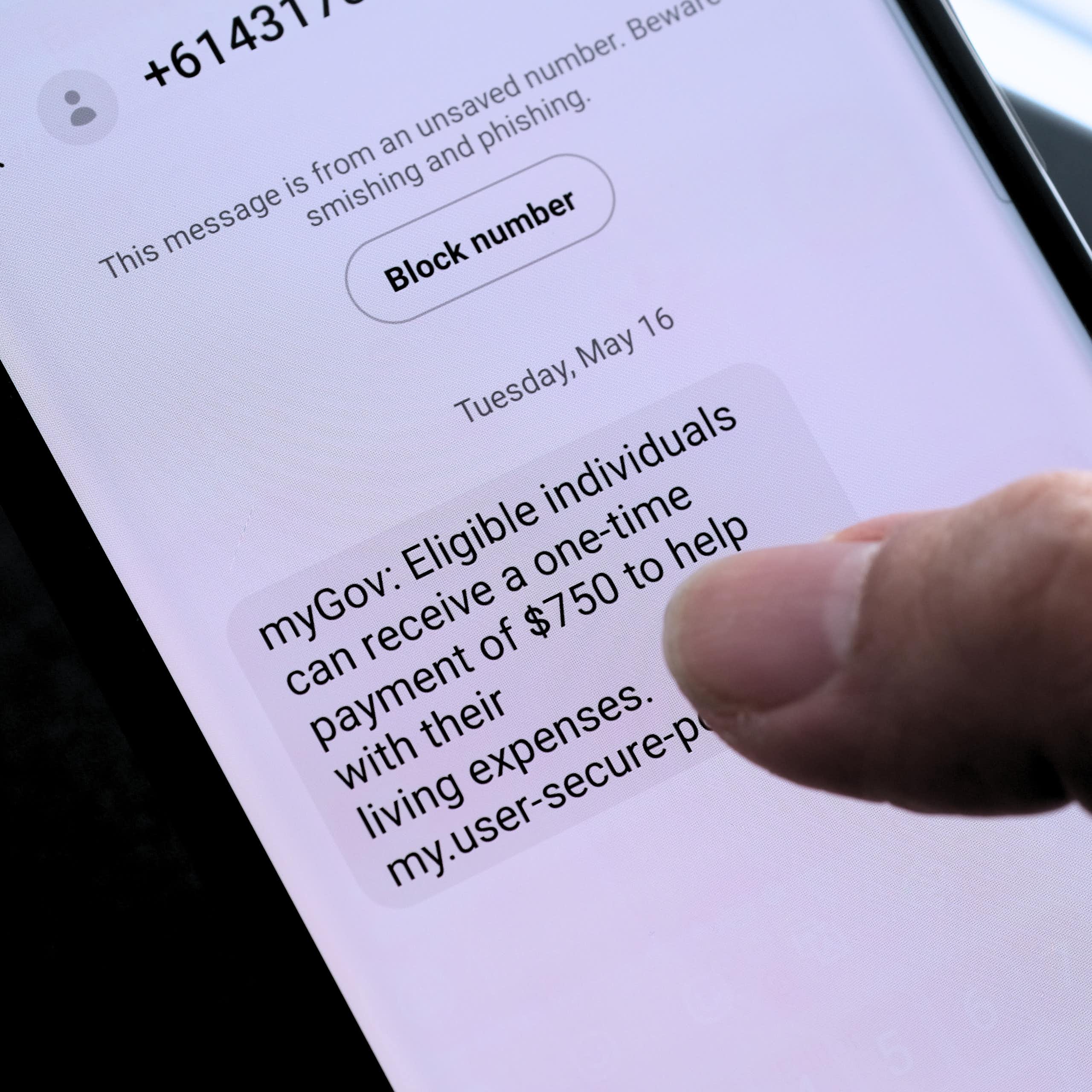 A person reading a text that advises them of a fake myGov payment.