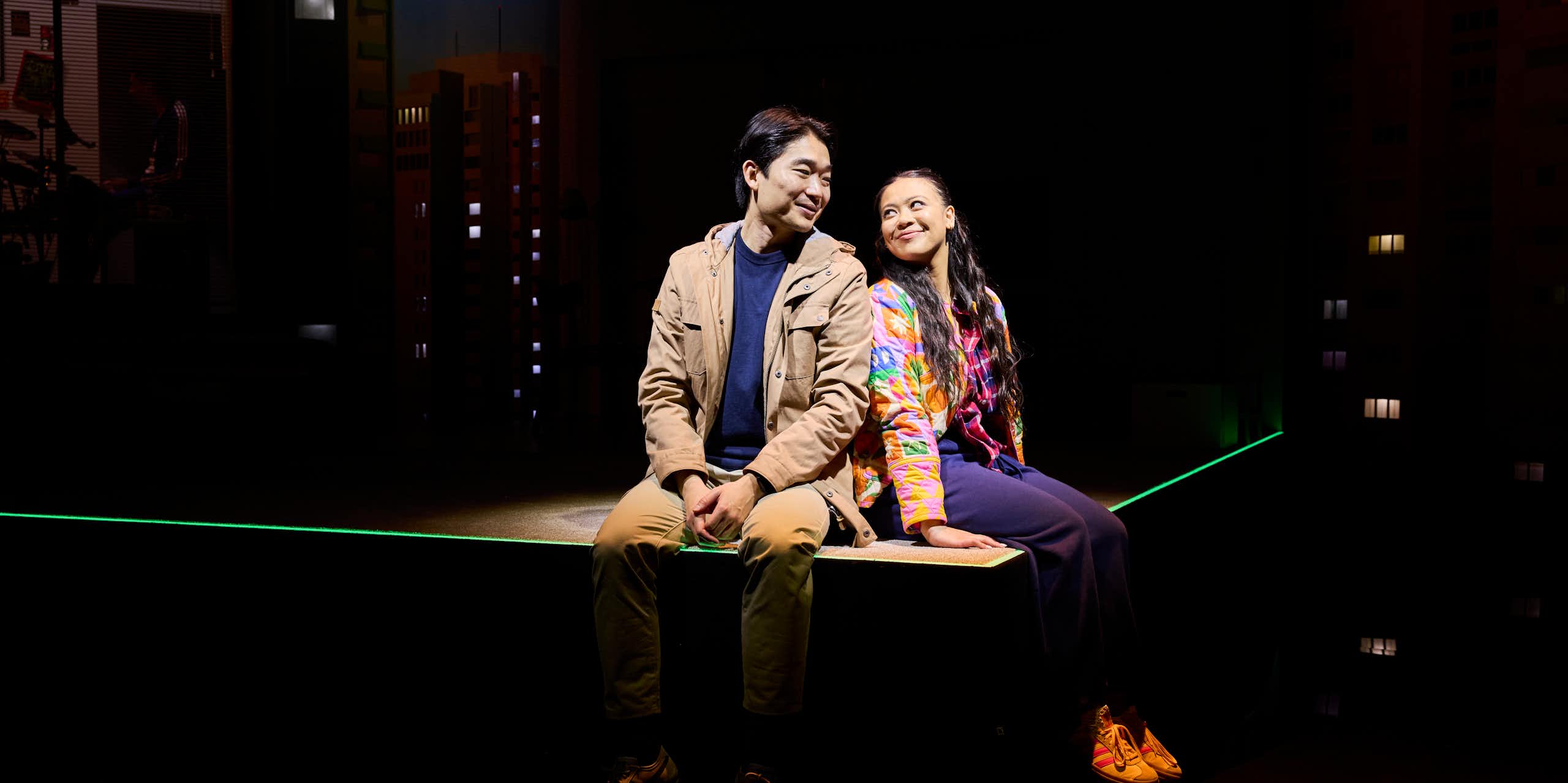 A man and woman sit on a stage