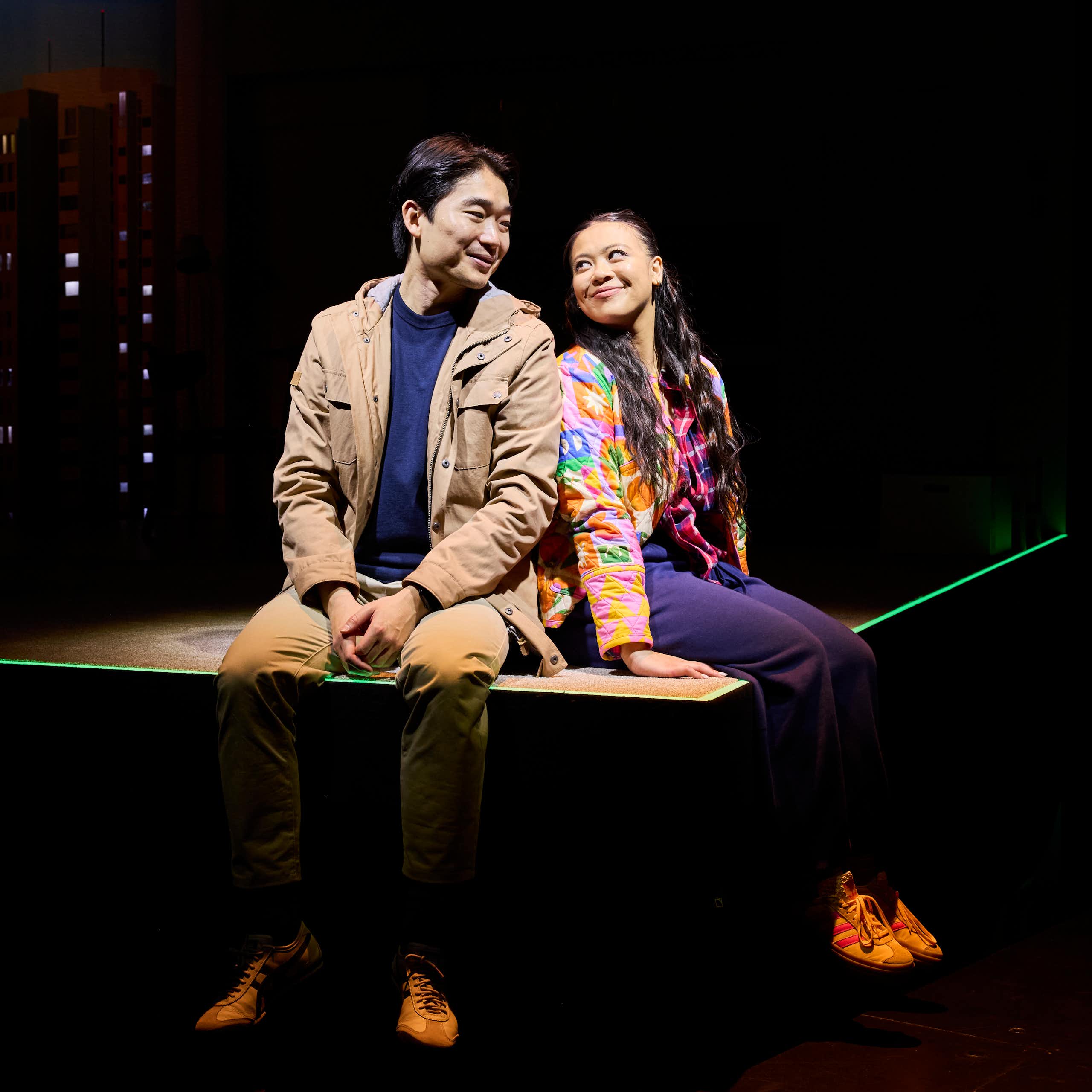 A man and woman sit on a stage