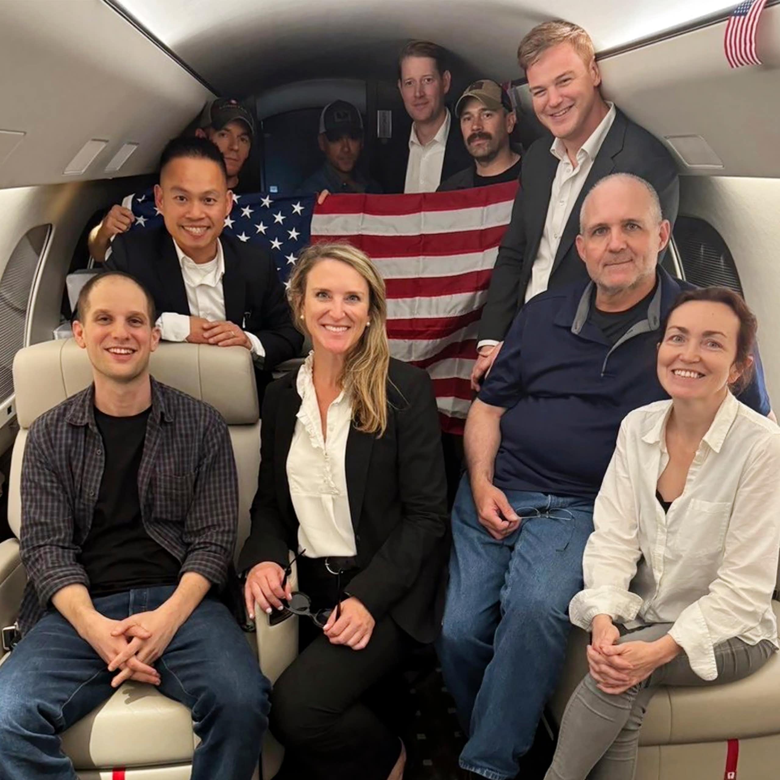 A group of people in a private jet holding an American flag