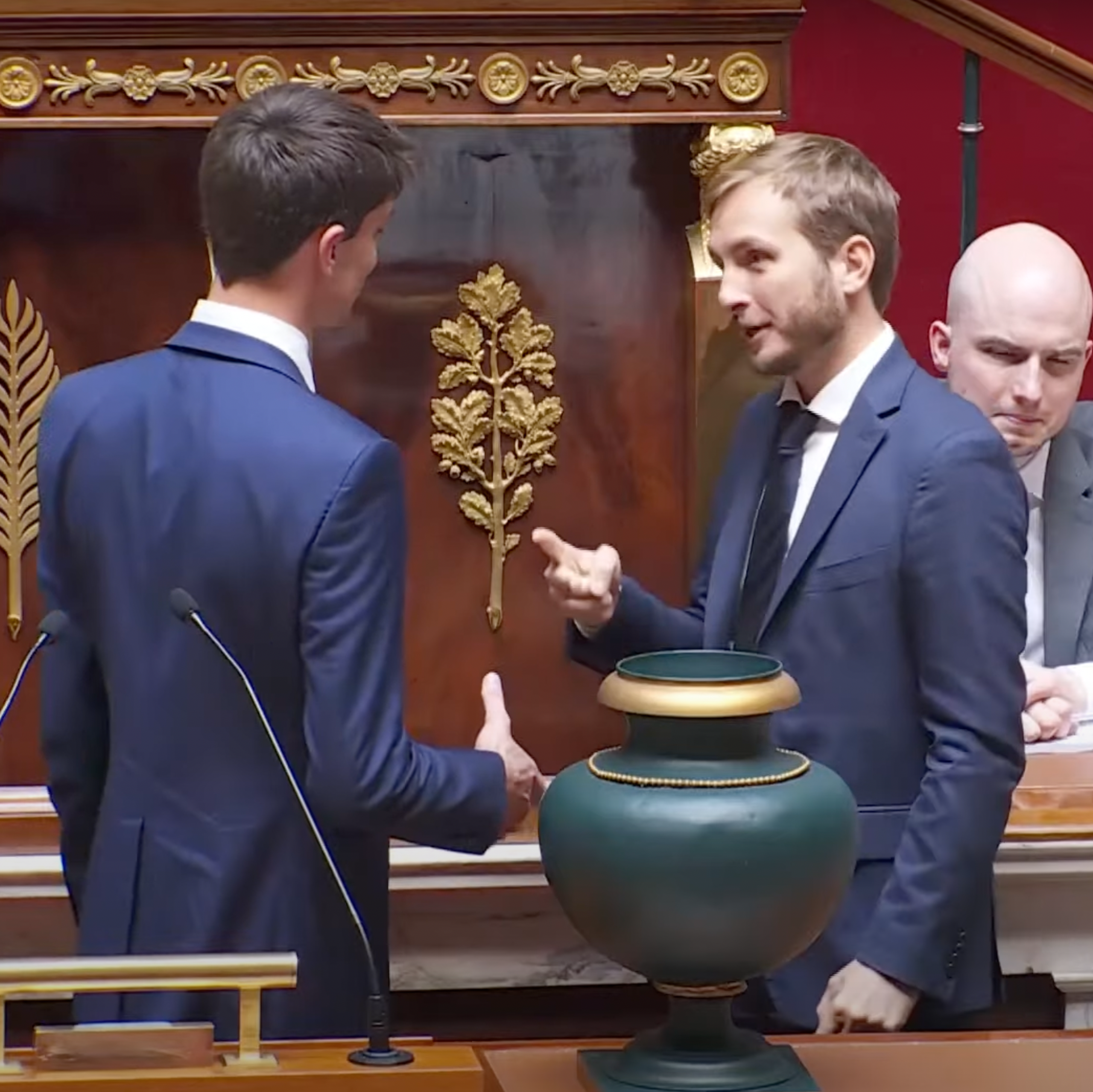 A man holding his hand out to shake and François Piquemal holding his hand in the shape of scissors in response.